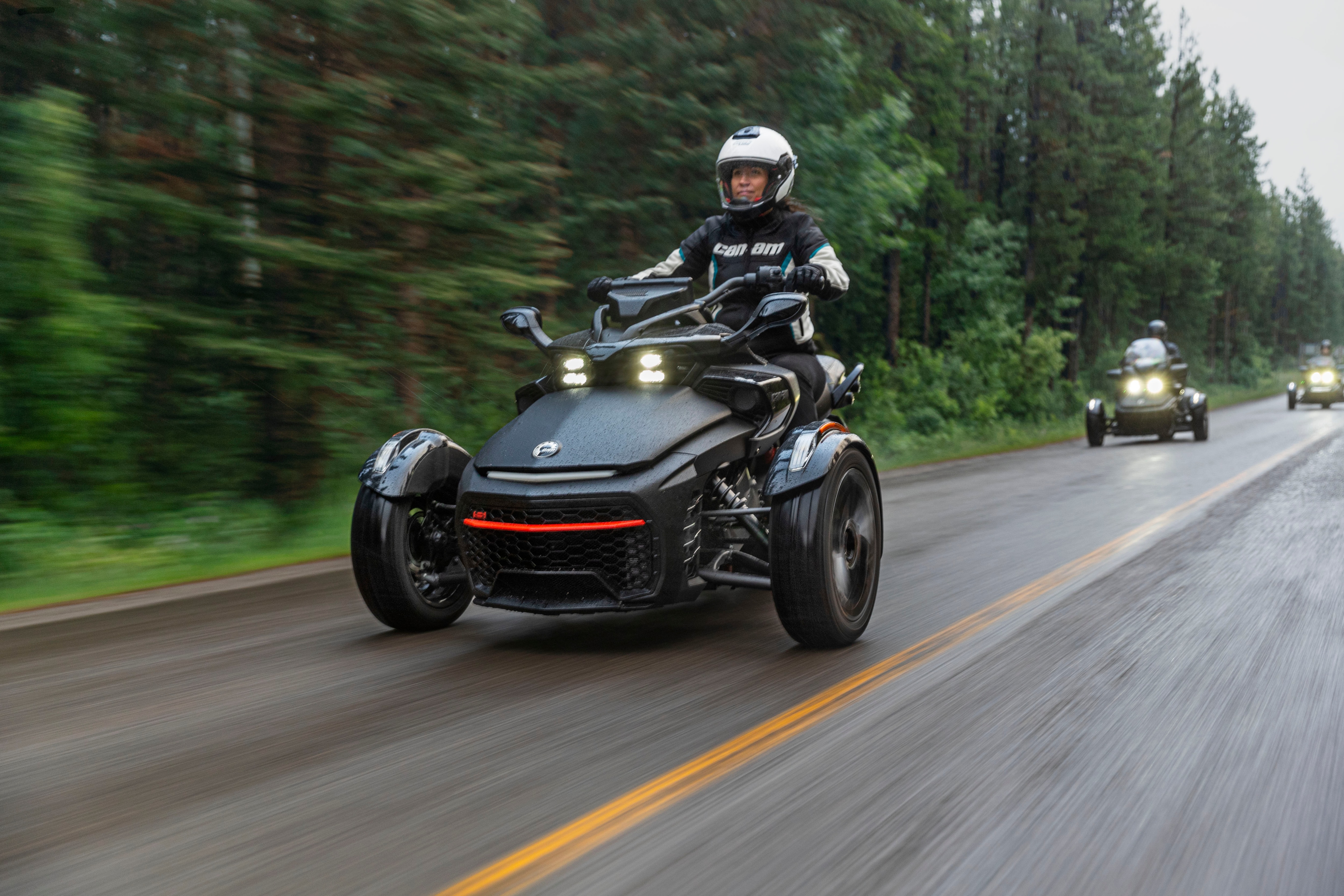 Several Can-Am Spyder F3-S with their lights on on the road