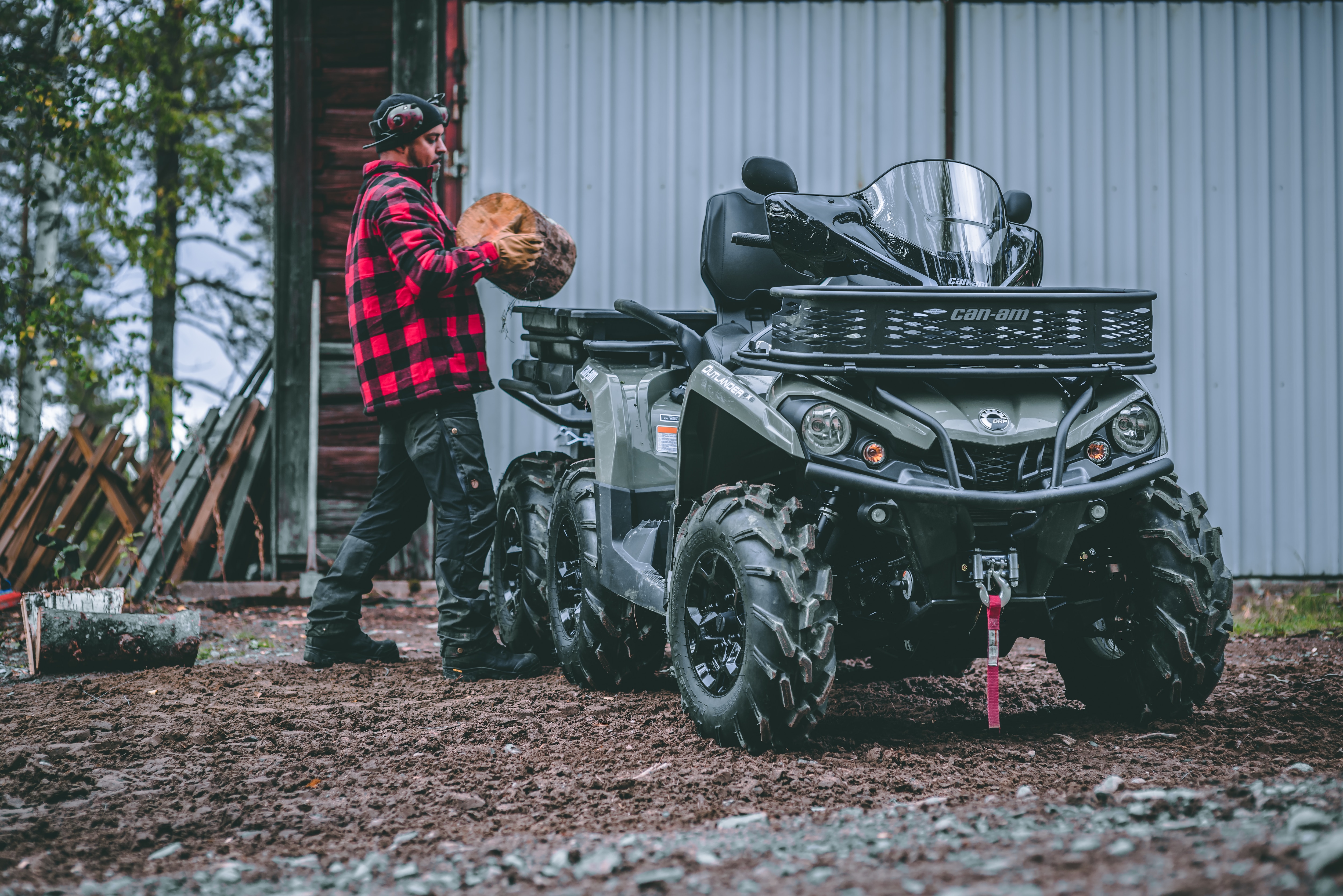 A man putting wood in a basket in the back of his Can-Am Outlander 6x6 PRO ATV
