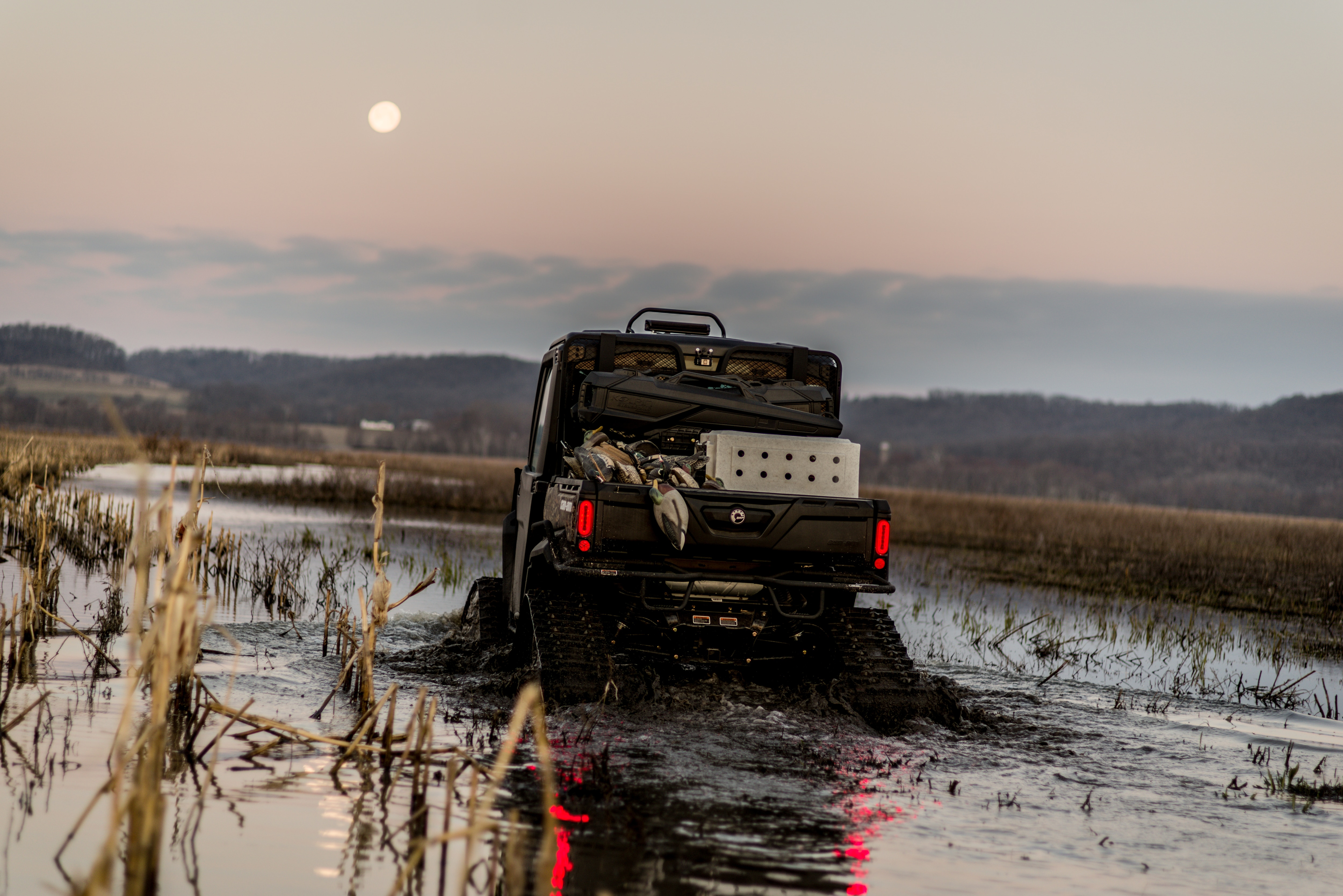 Rear view of a custom hunting Can-Am Defender rolling in water