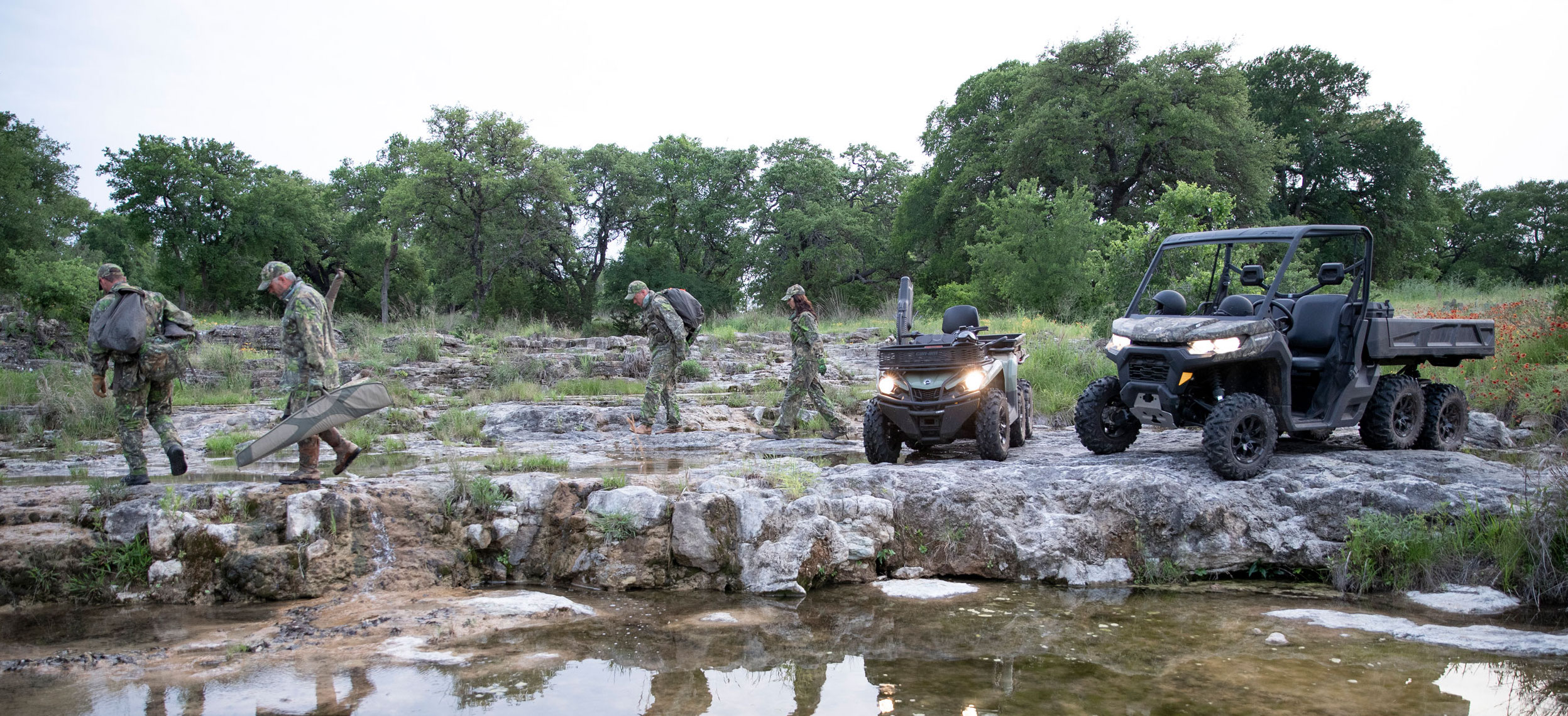 A group of hunters walking beside their Can-Am Outlander ATV and Can-Am Defender side-by-side