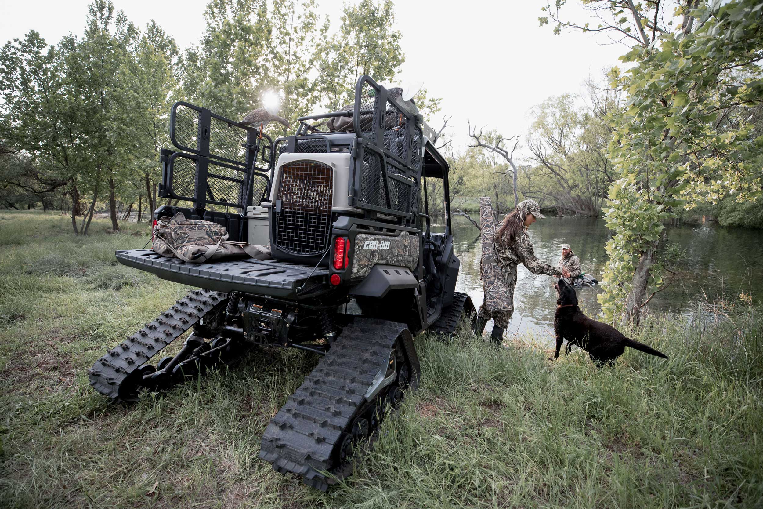 Vue arrière d'un Can-Am Defender de chasse personnalisé et d'un couple et leur chien