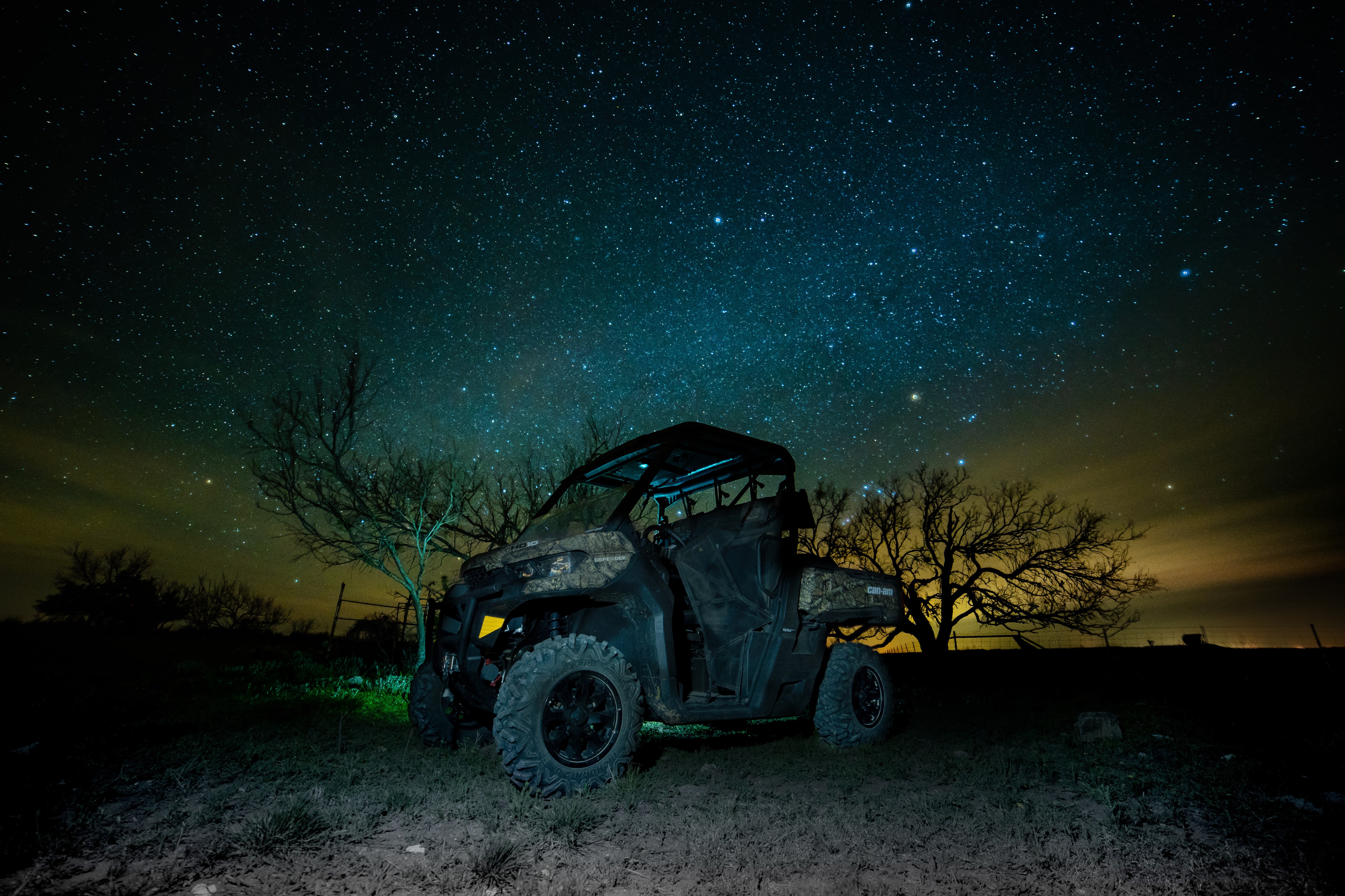 Un Can-Am Defender Mossy Oak Edition dans le noir avec un ciel étoilé