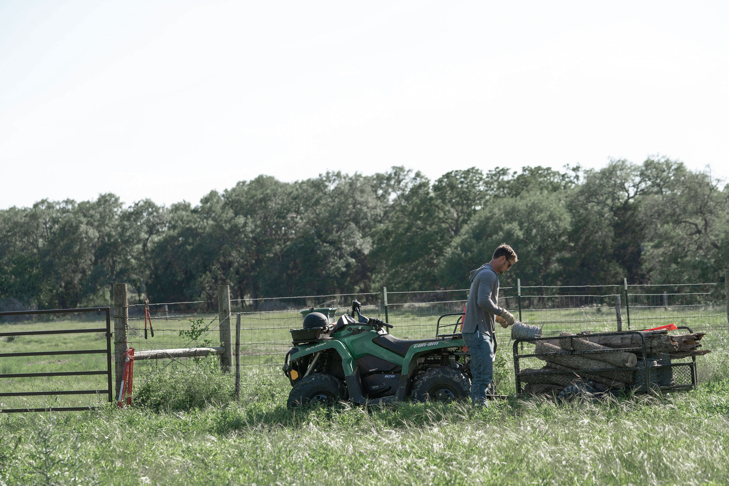 A Can-Am Outlander ATV and a man feeding cattle