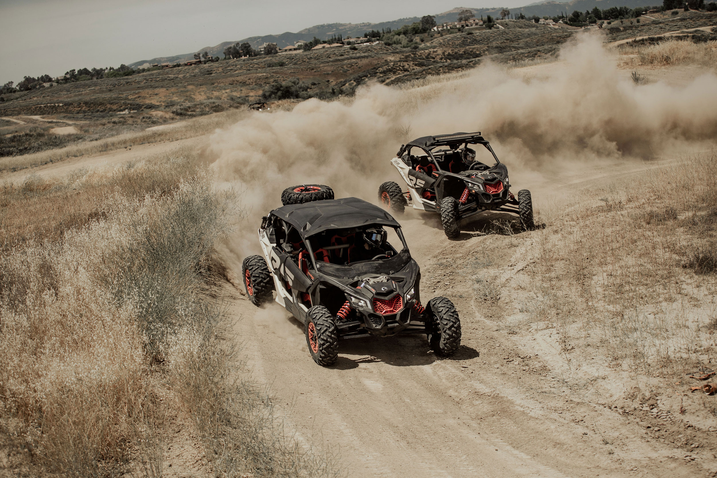 Two Can-Am Maverick X3 X rs side-by-sides drifting in a trail