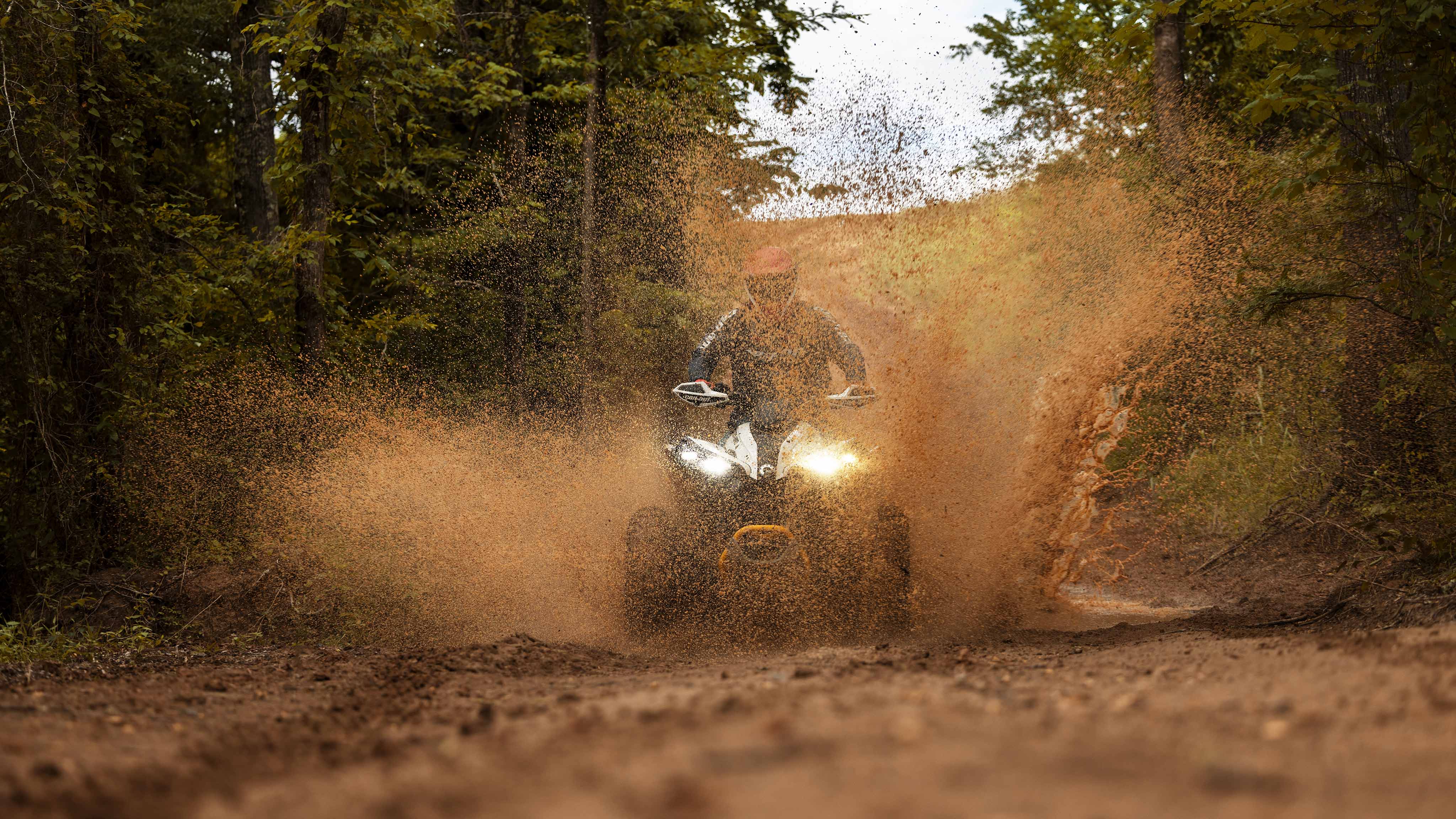 A Catalyst Gray and Neo Yellow Can-Am Renegade X MR 1000 kicking up mud in a mud hole