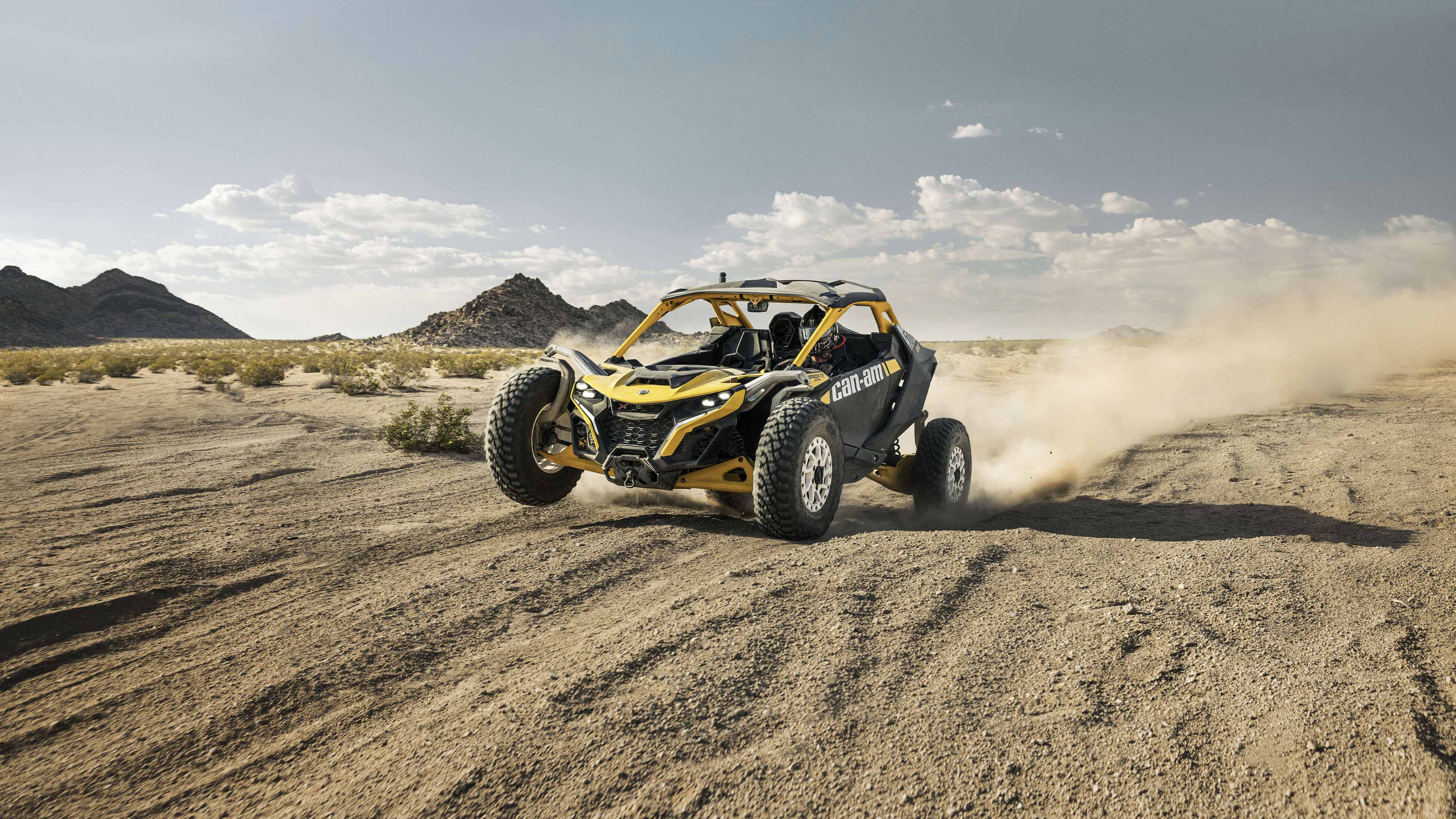 A Can-Am Maverick R X RS 2024 with tall knuckle suspension speeding through the desert.