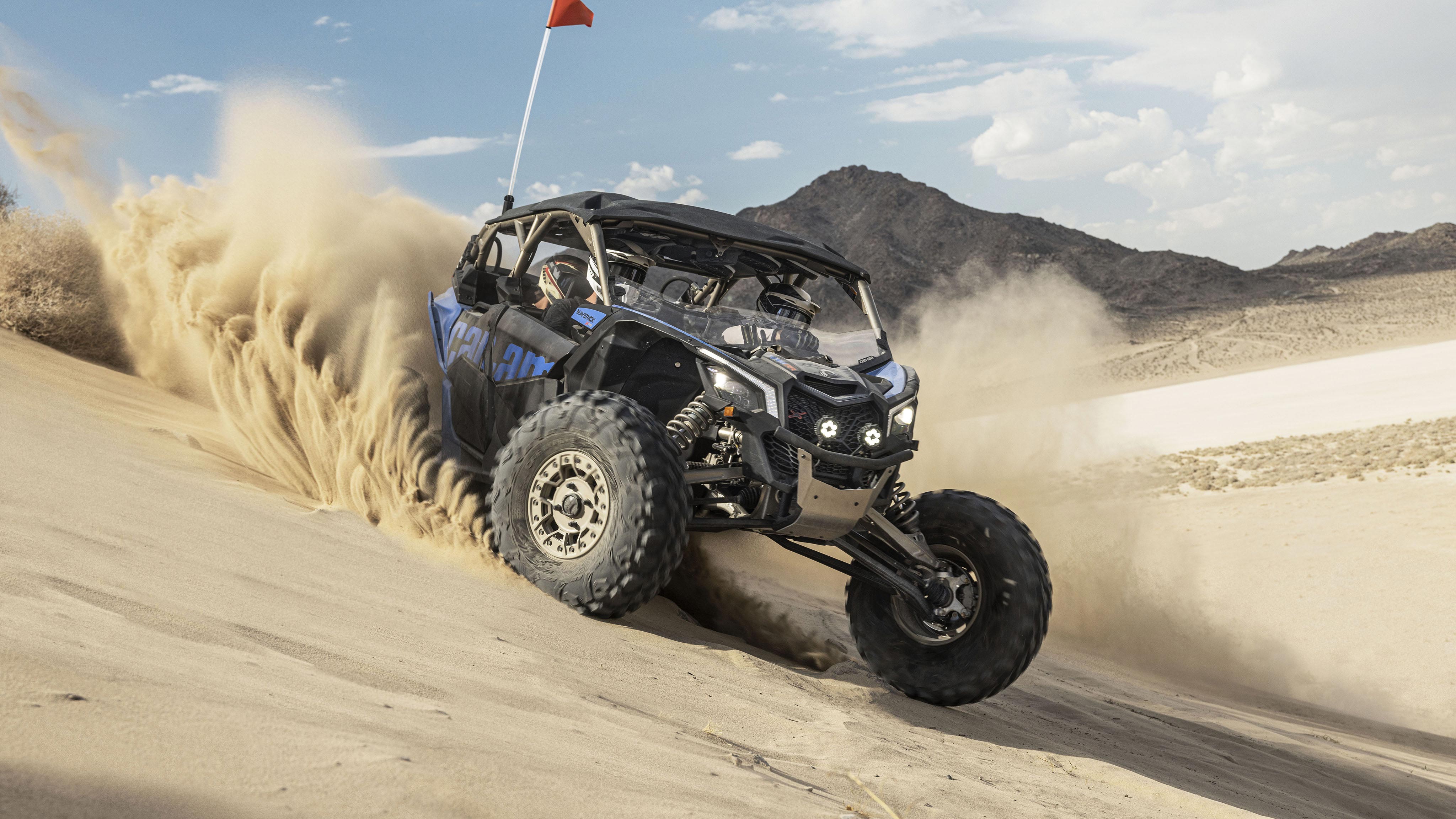 Un Can-Am Maverick X3 avec suspension Smart-shox dévalant une dune de sable. 