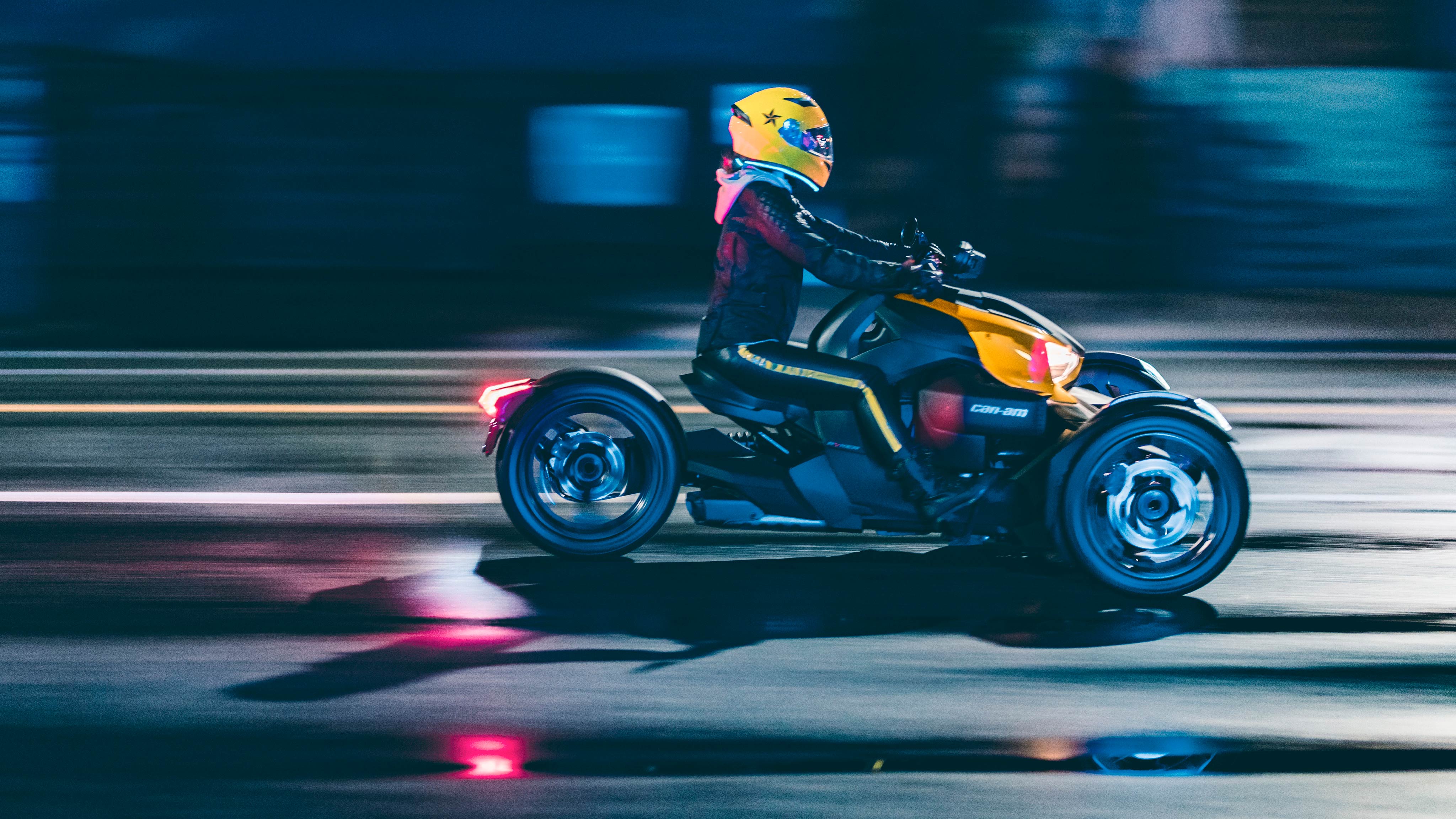 Woman riding Can-Am Ryker vehicle with yellow helmet