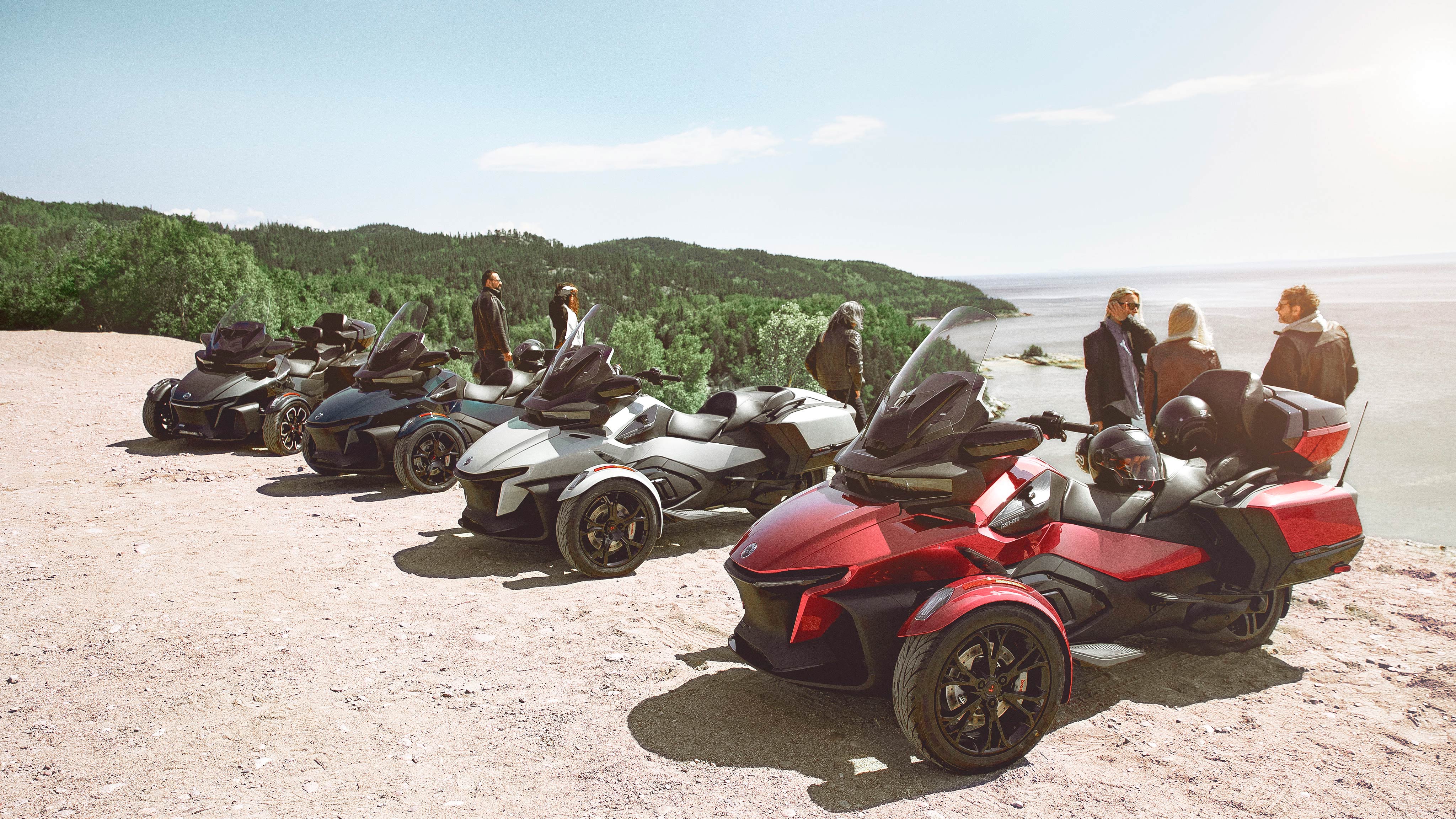 People chatting around 4 2020 Can-Am Spyder RT models, in front of a cliff