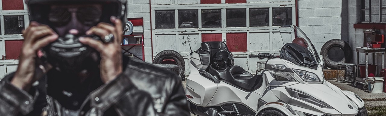 Homem colocando o capacete ao lado do seu Can-Am Spyder RT