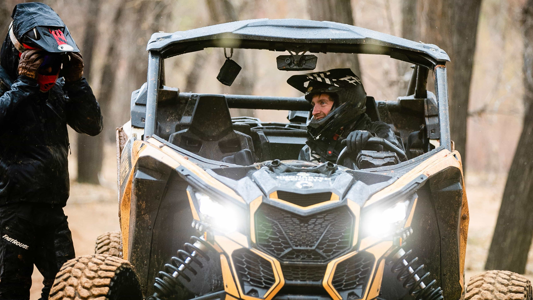 A man seated in a muddy SSV