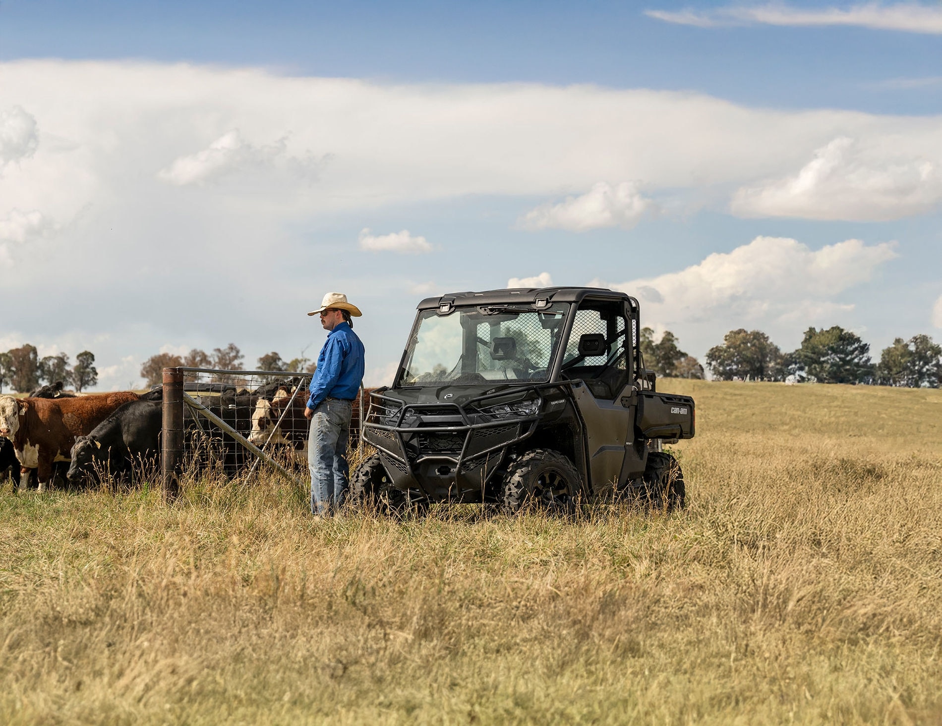 A farmer taking a break near his Can-Am Defender alongside cows