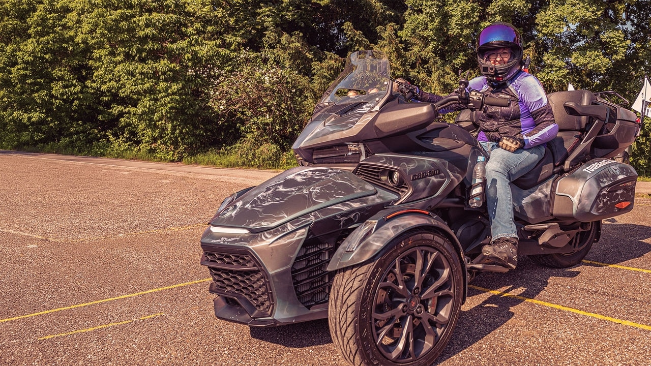 Can-AM 3-wheeled vehicle on a road passing in front of a gas station 