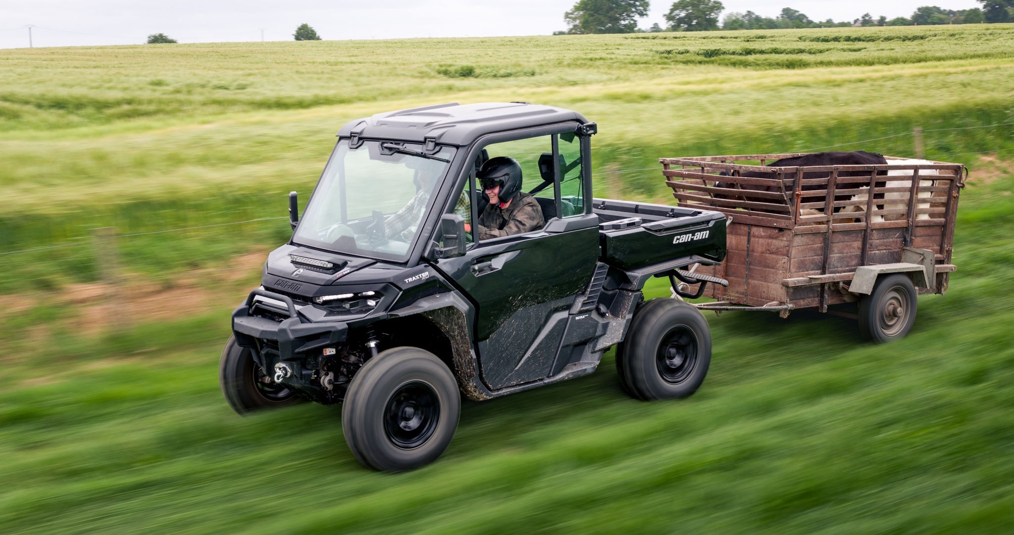 Twee personen rijden in een Can-Am Traxter SxS-voertuig in een veld