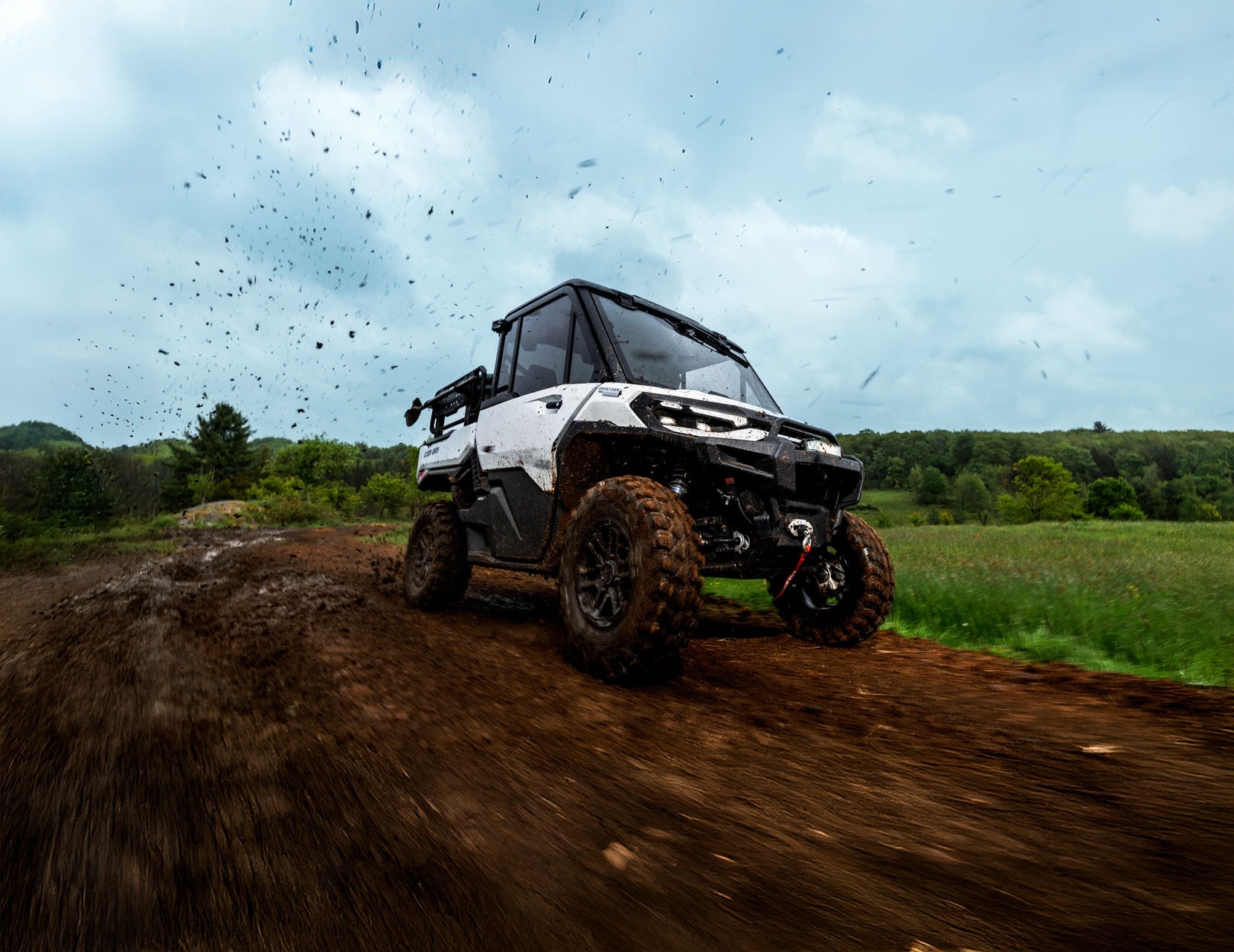 2026 Can-Am Defender HD11 Hybrid White driving on a dirt road