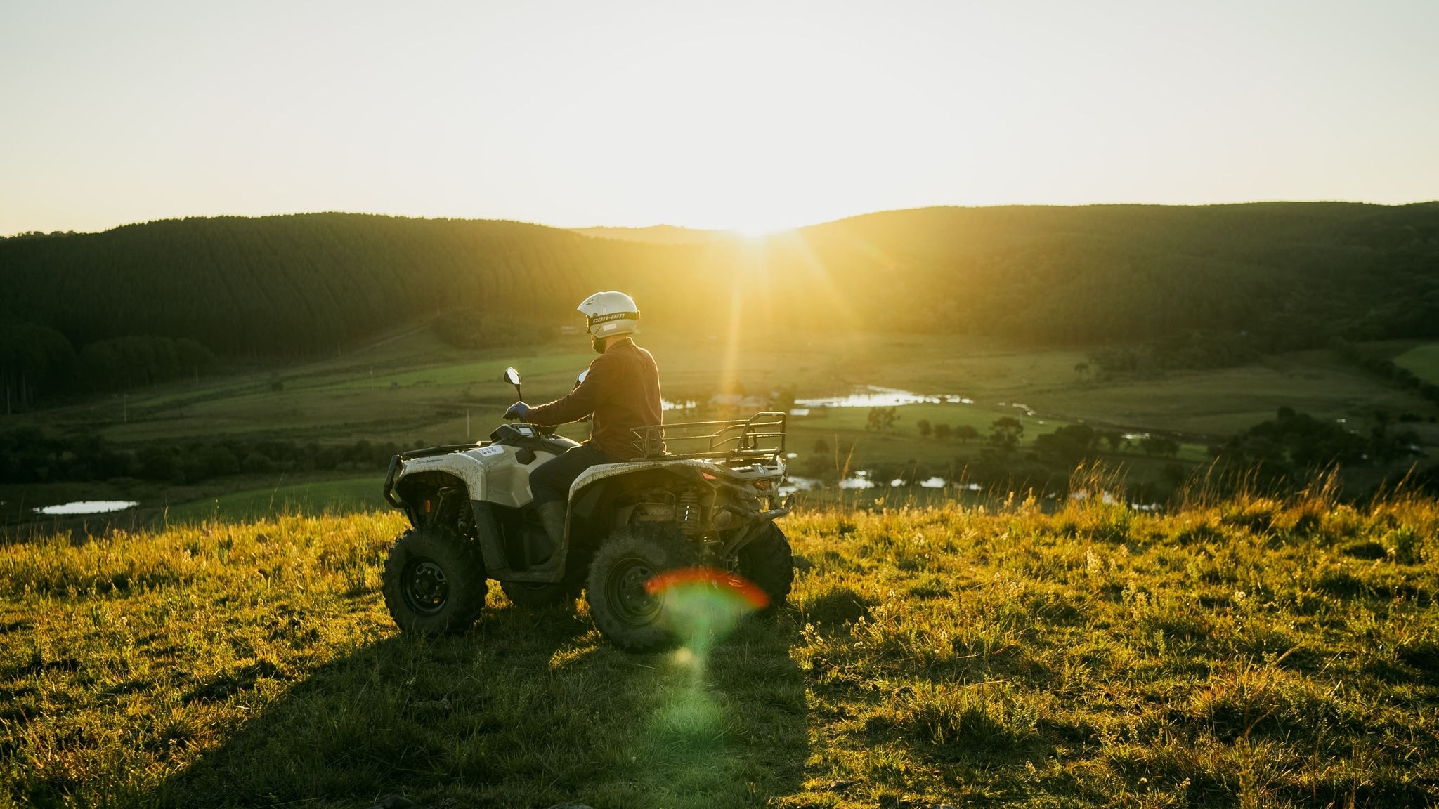 Piloto a bordo de um Can-Am Outlander Pro estacionado no campo.