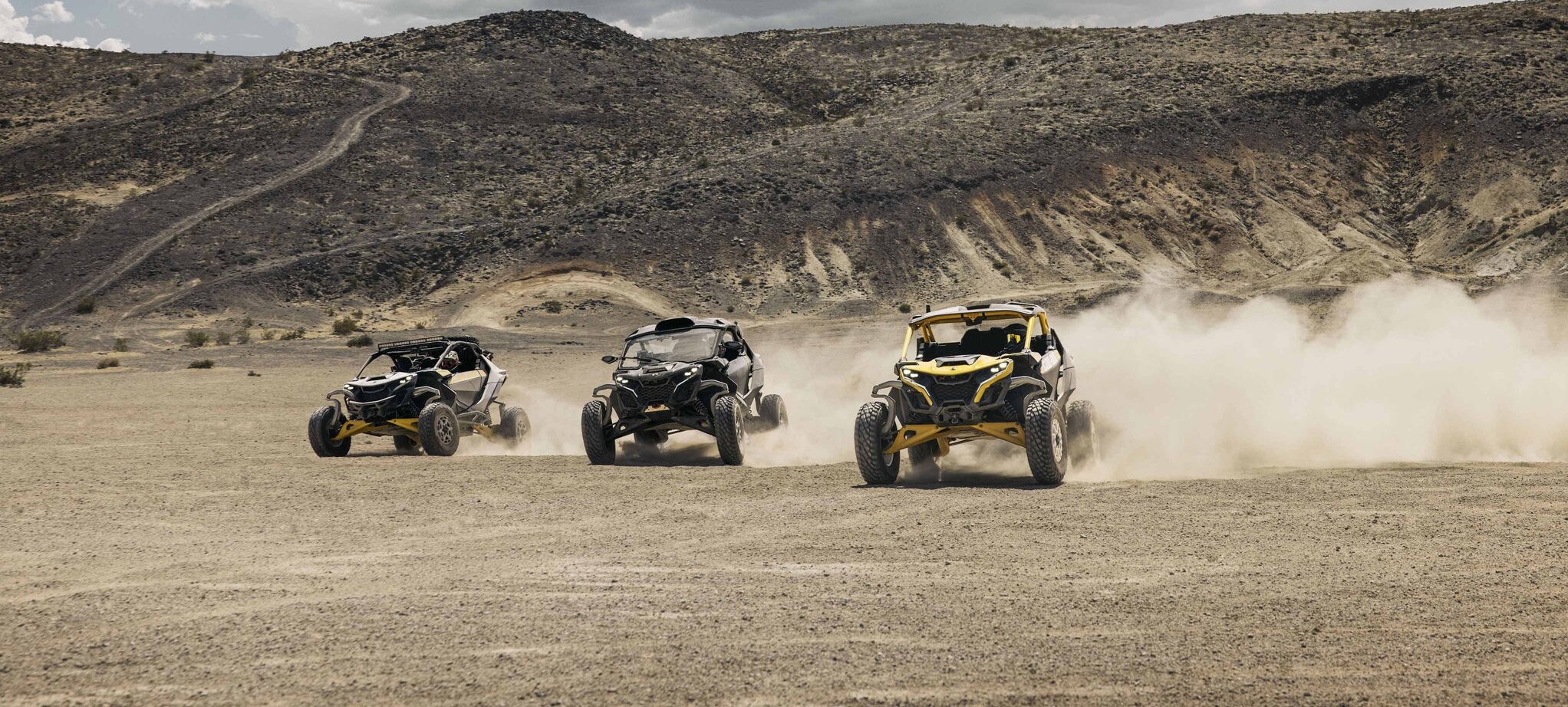 Three Can-Am Maverick R SxS vehicles racing through the desert