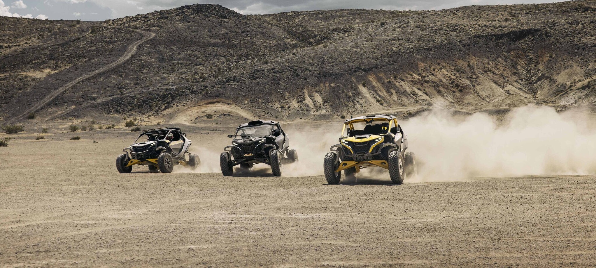 Three Can-Am Maverick R SxS vehicles racing through the desert