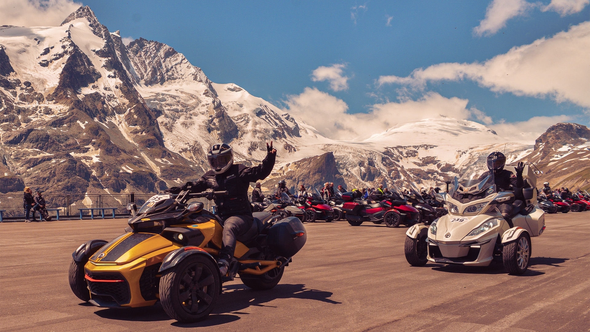 Dozens of three-wheeled Can-Am 3-wheelers parked in front of snow-capped mountains during a community event