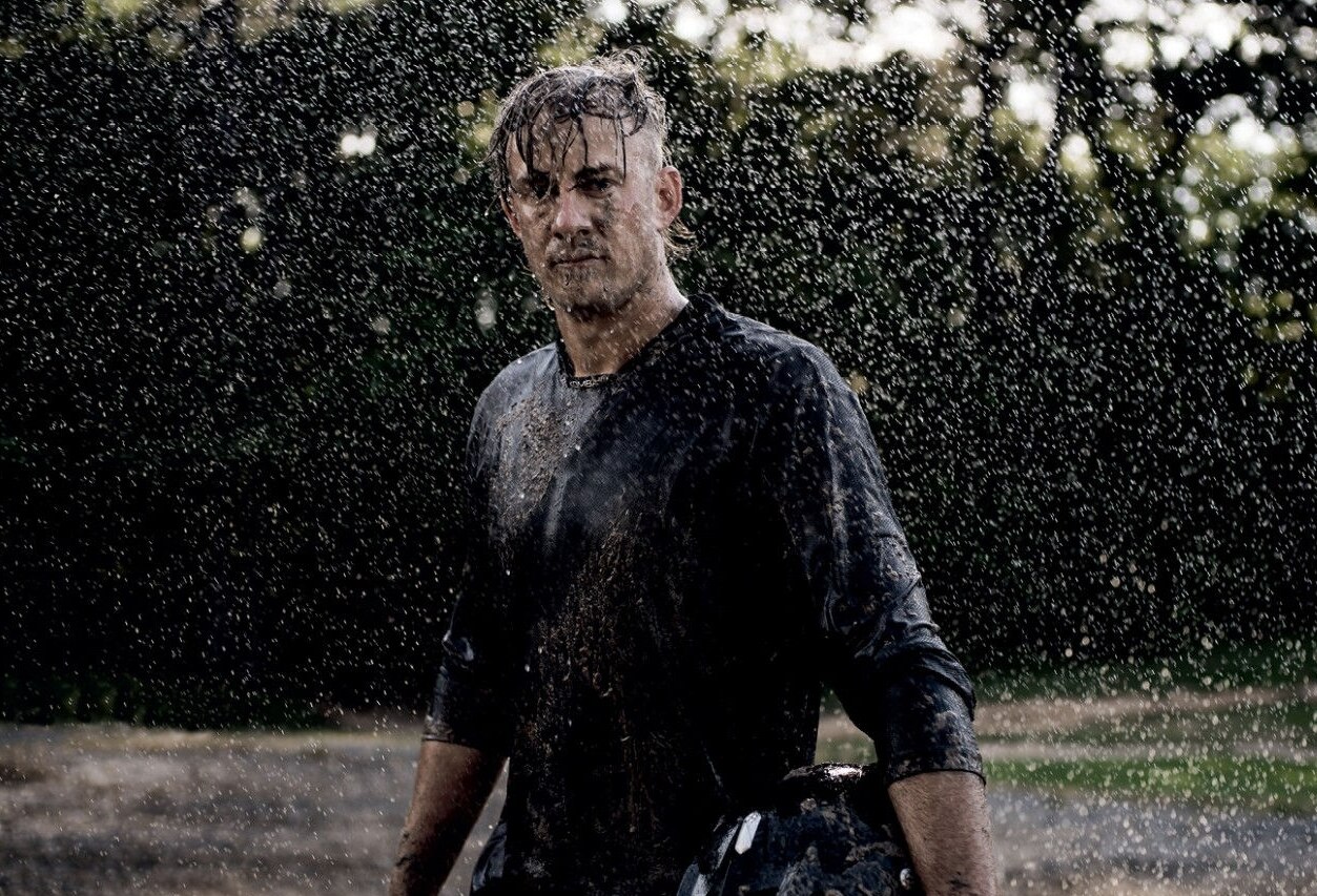 Un hombre sosteniendo un casco bajo la lluvia 