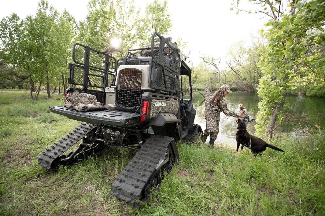 Rear view of a custom hunting Can-Am Defender and a couple and their dog
