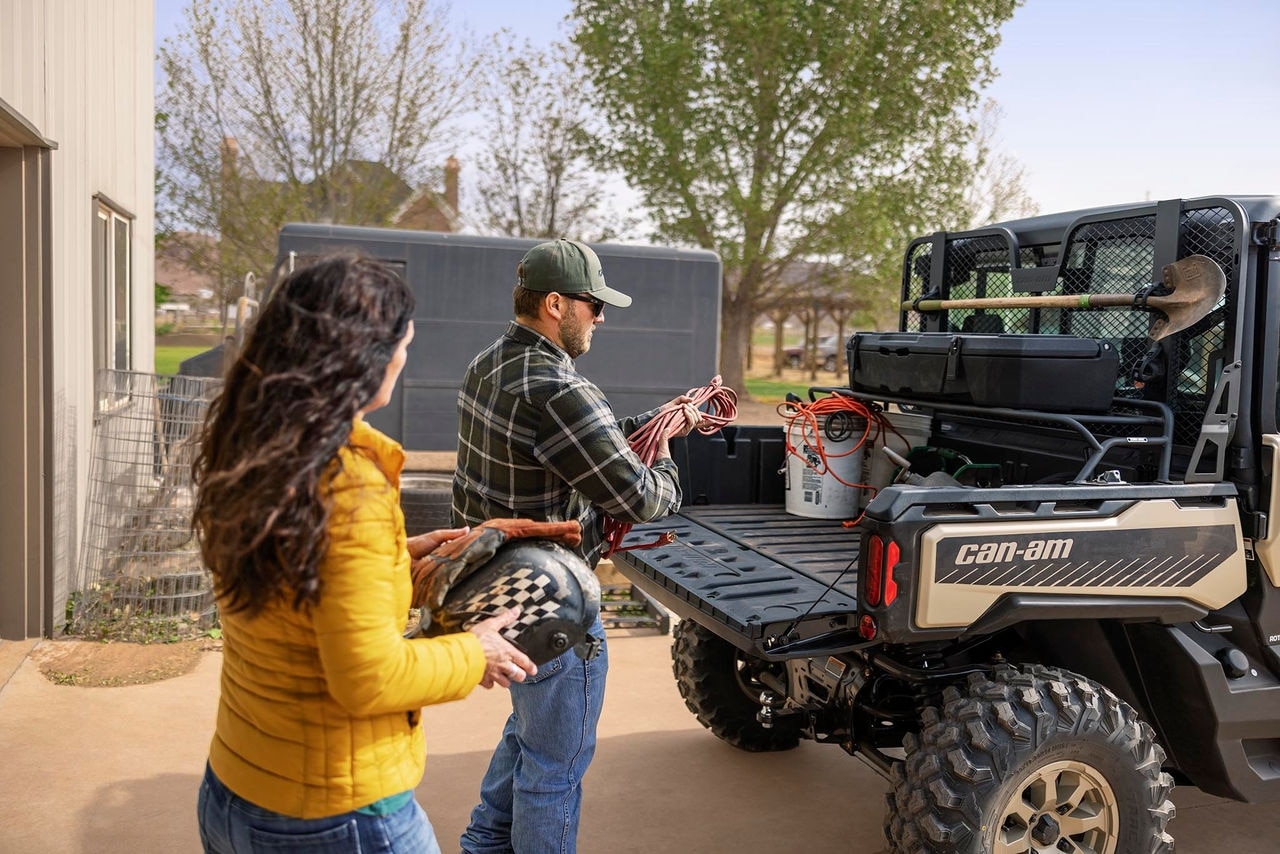 Un hombre y una mujer cargan la carga en su Can-Am Defender