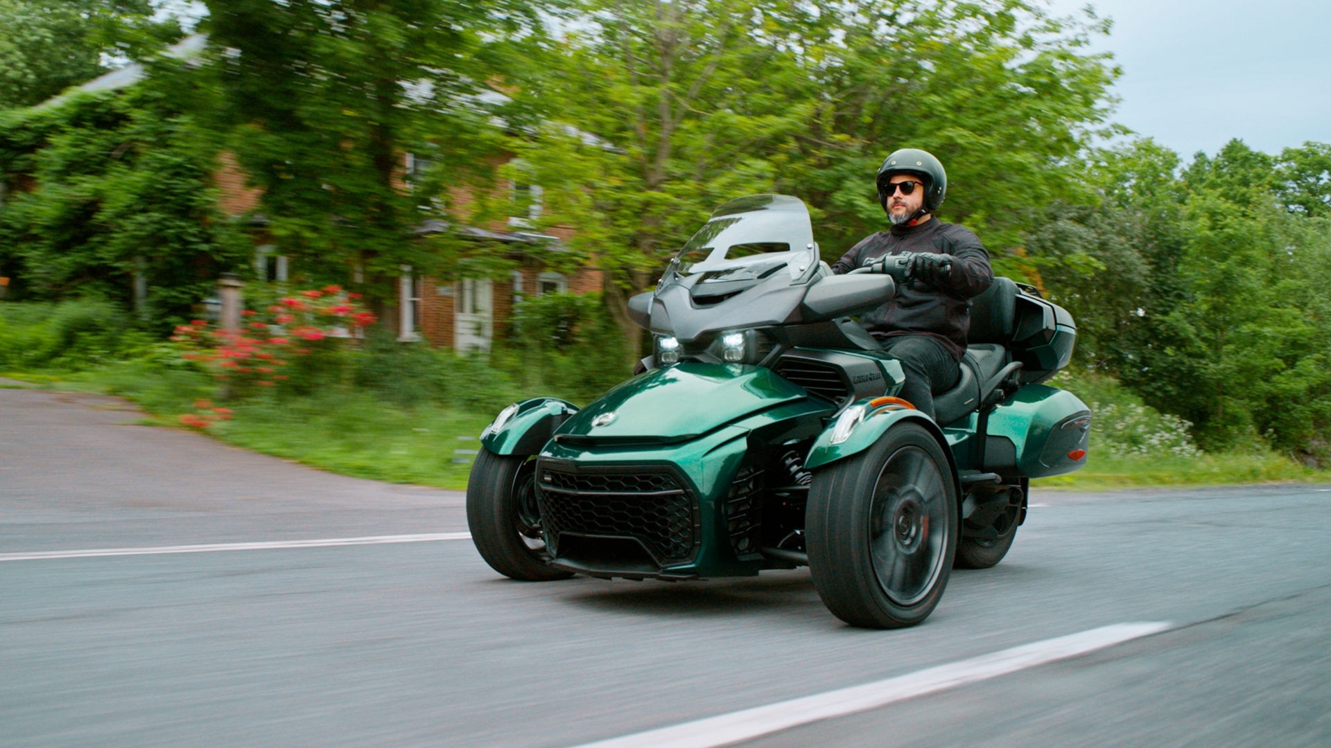 A driver testing a 2025 Can-Am Spyder F3 on an asphalt road