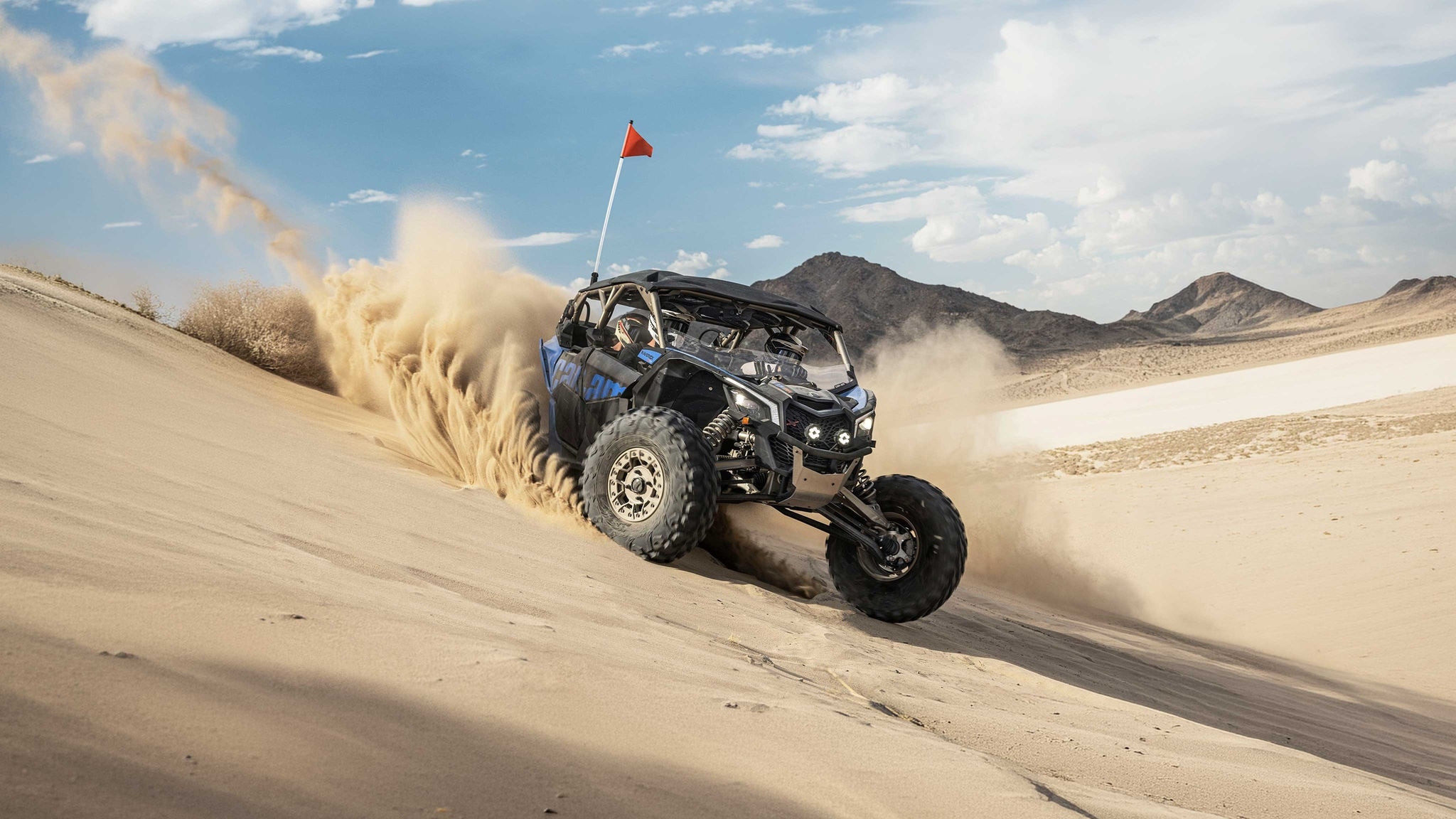 Vehículo Can-Am Maverick X3 SxS conduciendo sobre una duna de arena