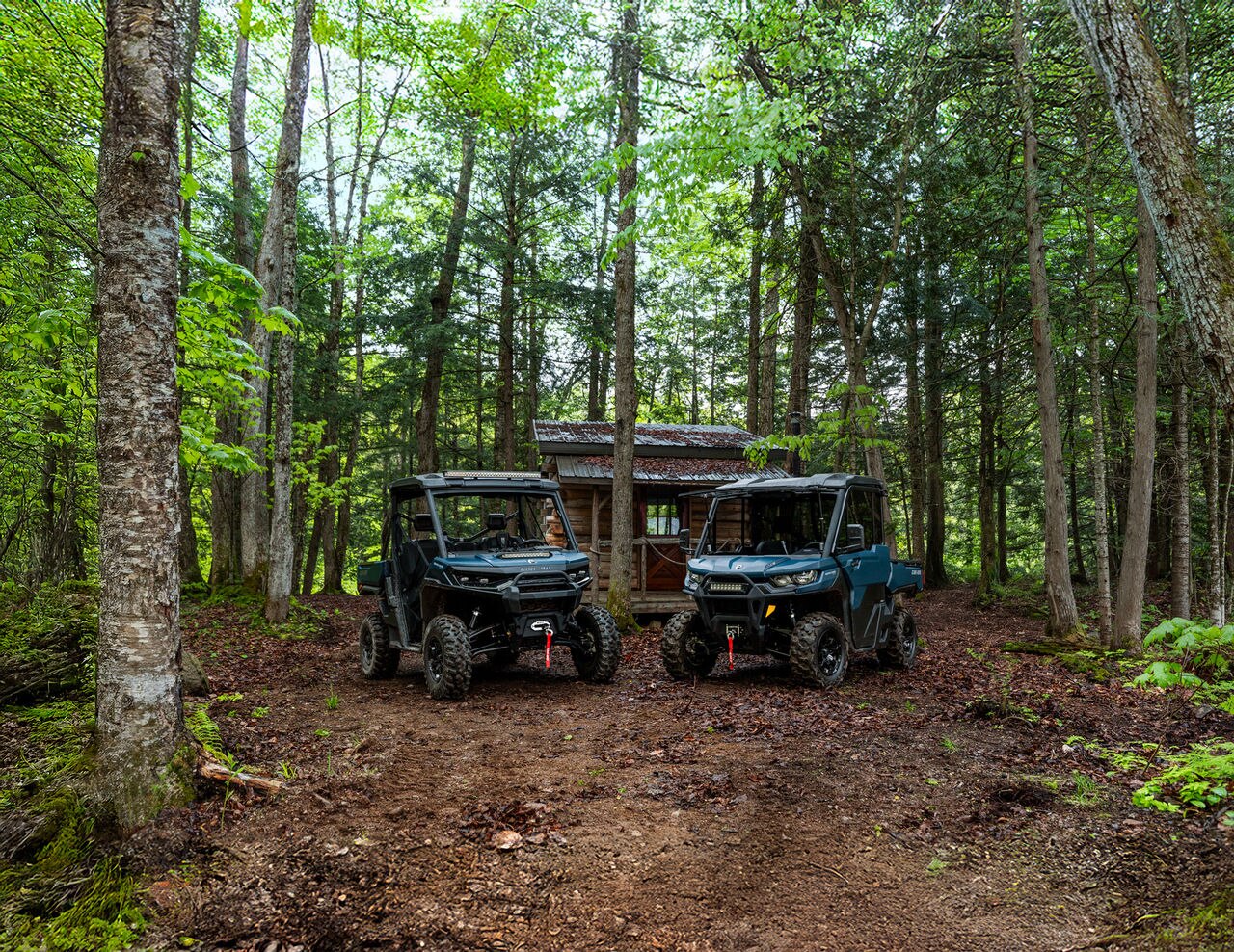 The two 2026 Can-Am Defender models parked side by side in the forest