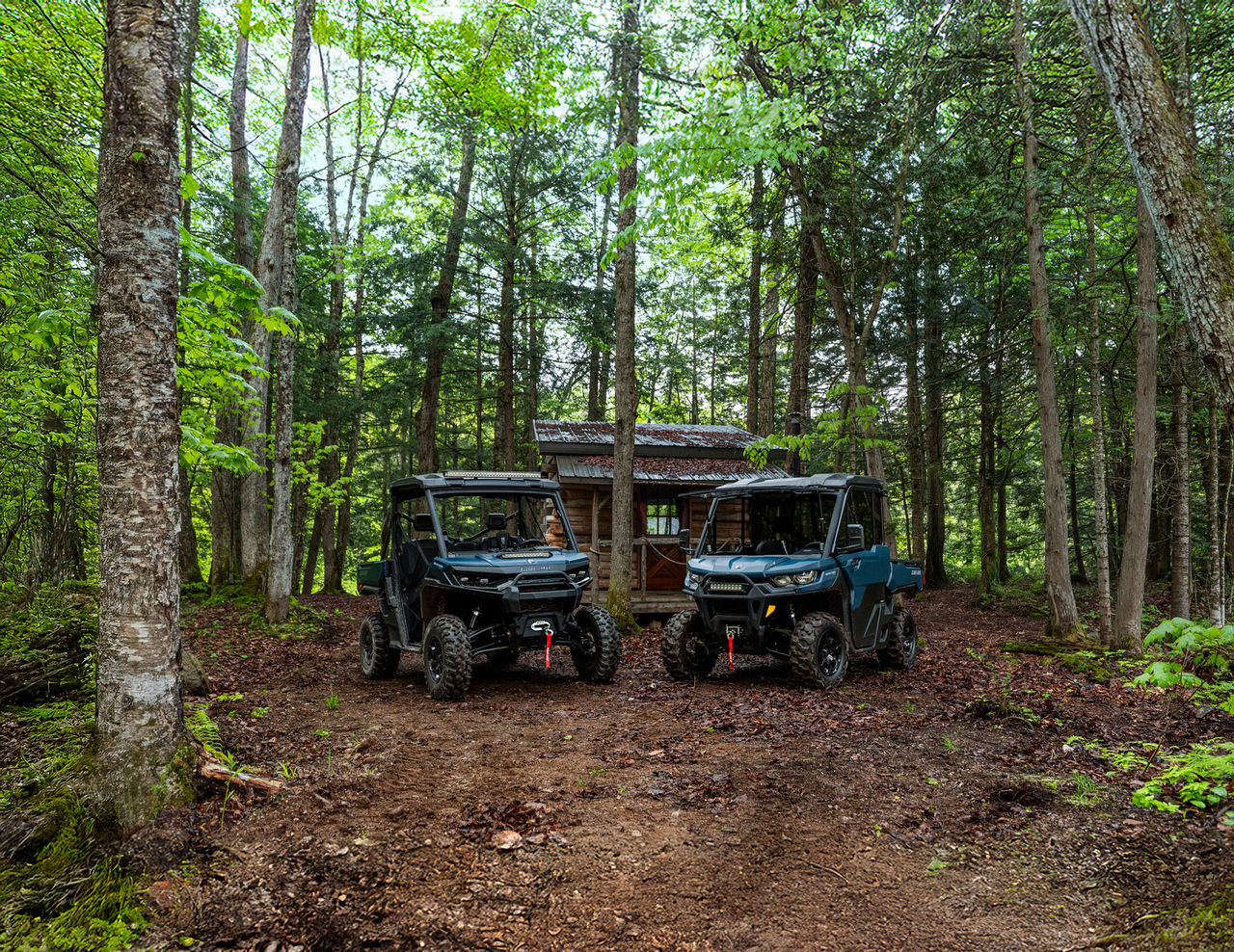 Dos vehículos Can-Am Defender SxS 2026 estacionados en un bosque