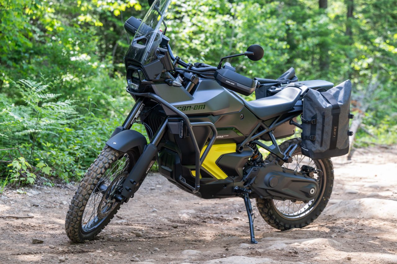 A Can-Am Origin electric motorcycle equipped with LinQ accessories, on a dirt road