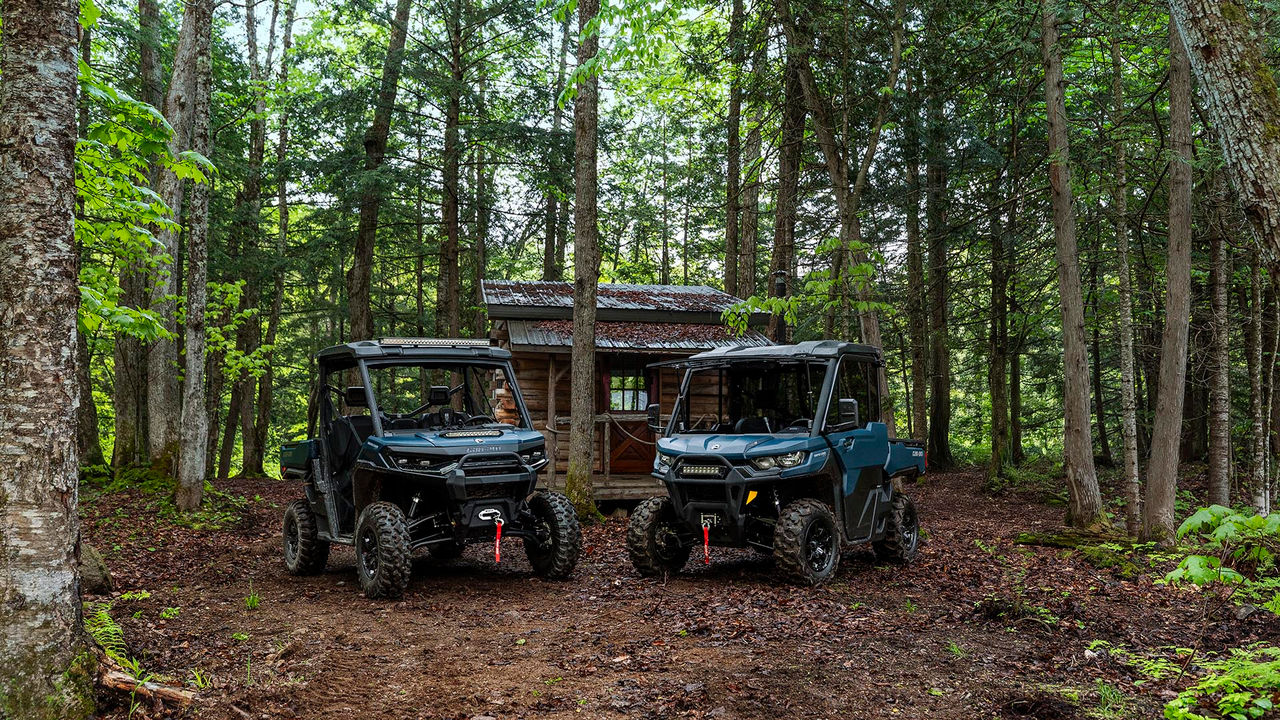 A 2026 Can-Am Defender HD11 hybrid white side-by-side vehicle in the forest