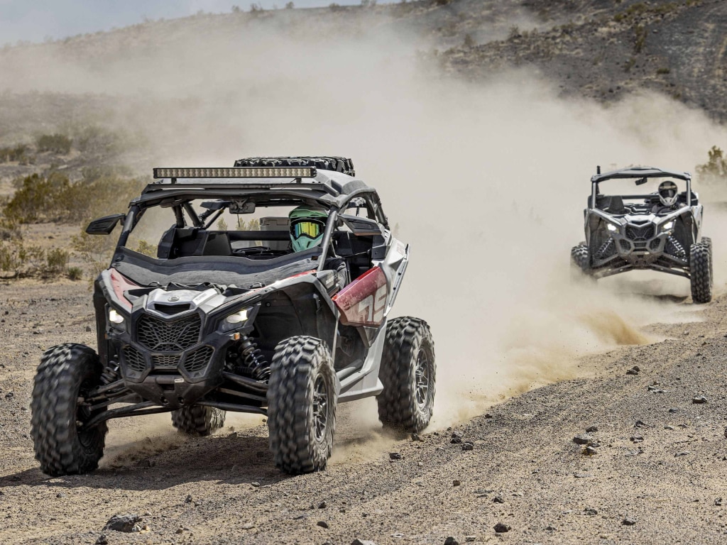 Two Maverick X3 SxS vehicles driving through the desert