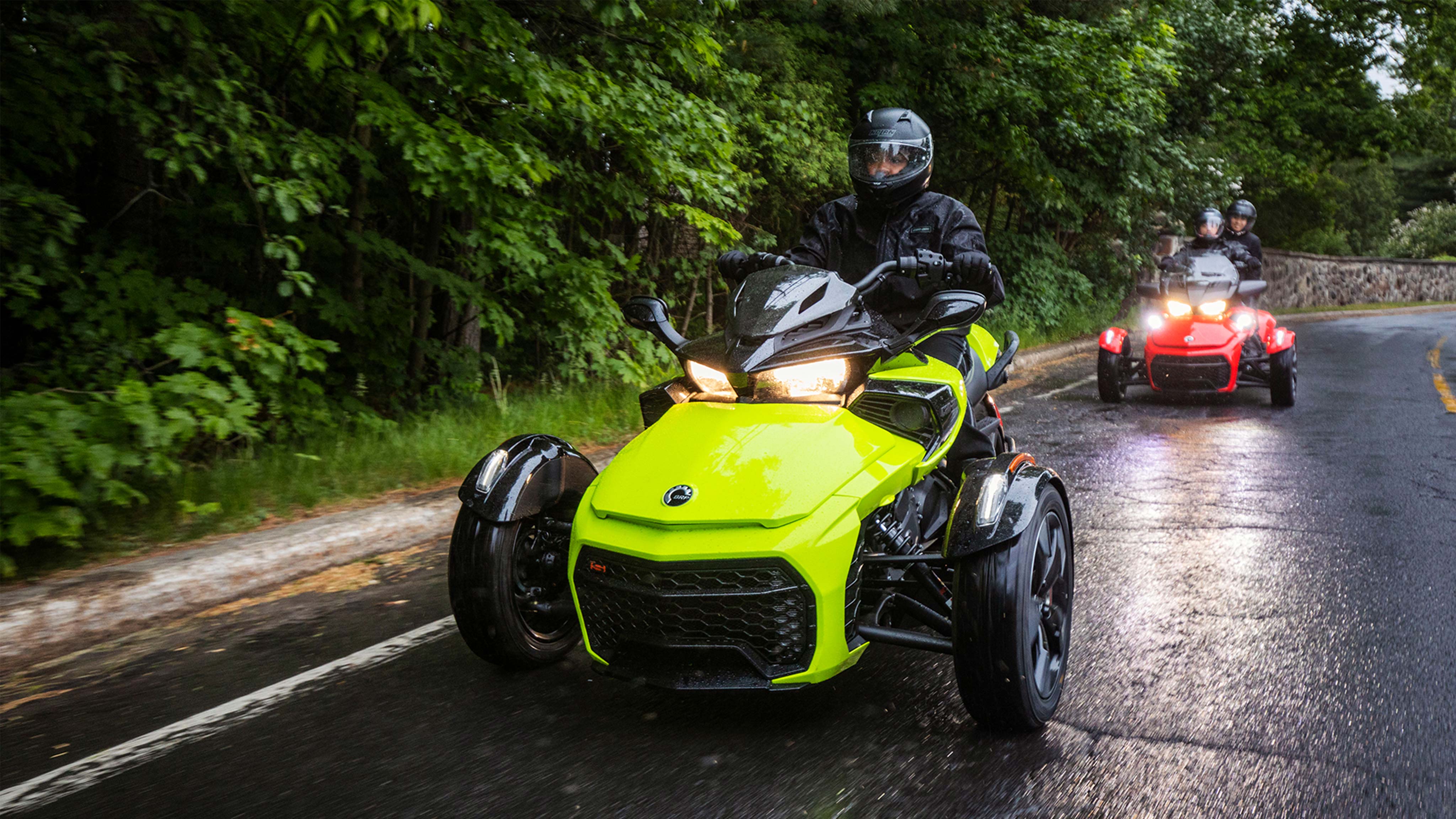 Yellow Can-Am F3 riding in the rain followed by a red Can-Am.