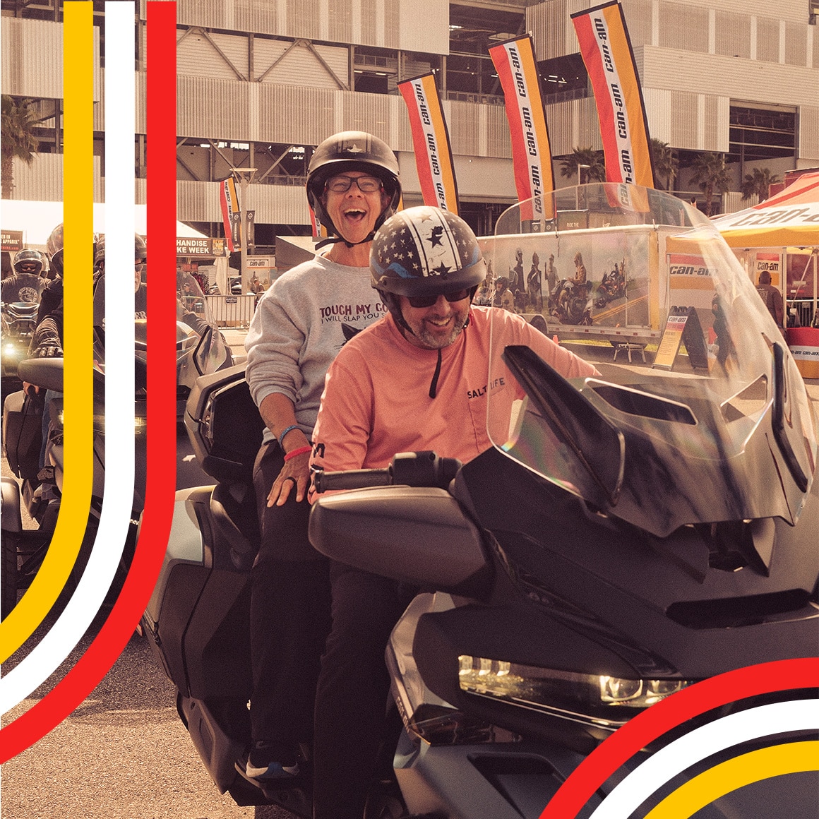 A smiling couple on their Can-Am three-wheeler at a community event