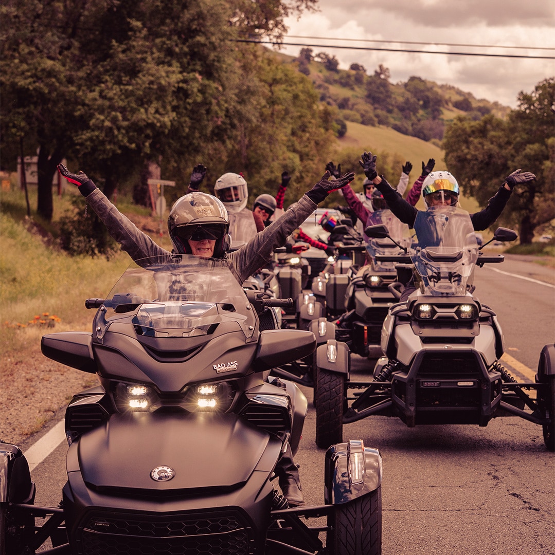 Several women with their arms in the air, proud to be riding Can-Am three-wheelers