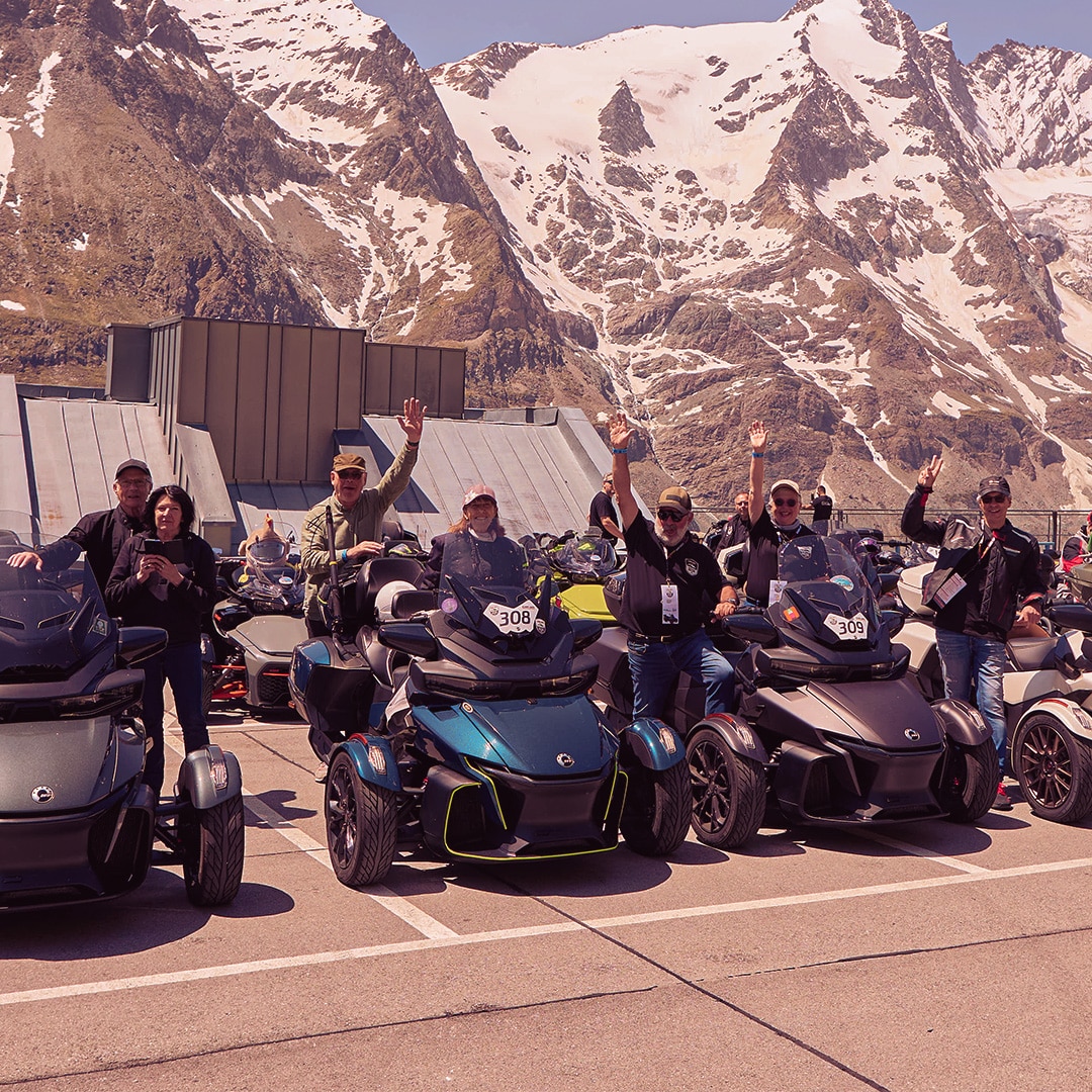 A group of riders at a community event, in front of a snow-covered mountain