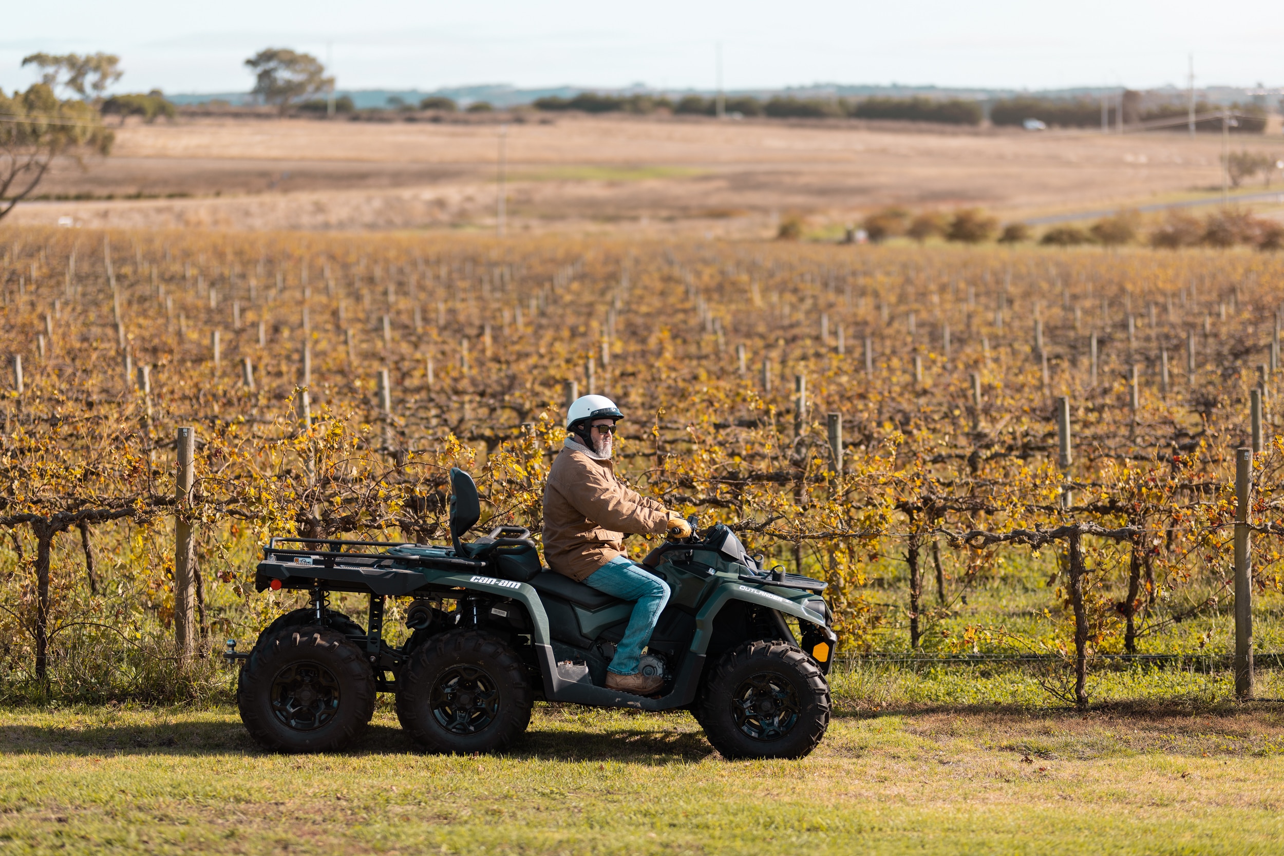 Man riding Can-Am Outlander 6x6 through a vineyard