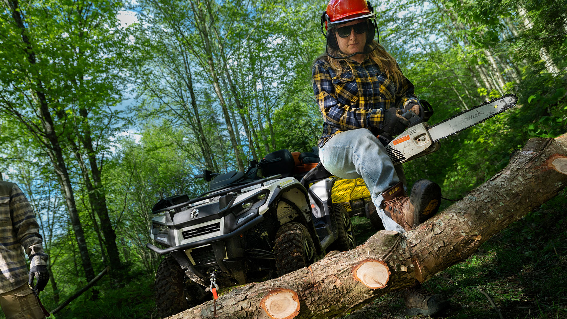 A woman cutting wood with a saw in front of her Can-Am Outlander Electric ATV