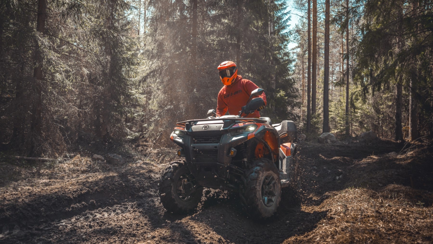 Tre Outlander ATV:er på en ojämn stig i skogen