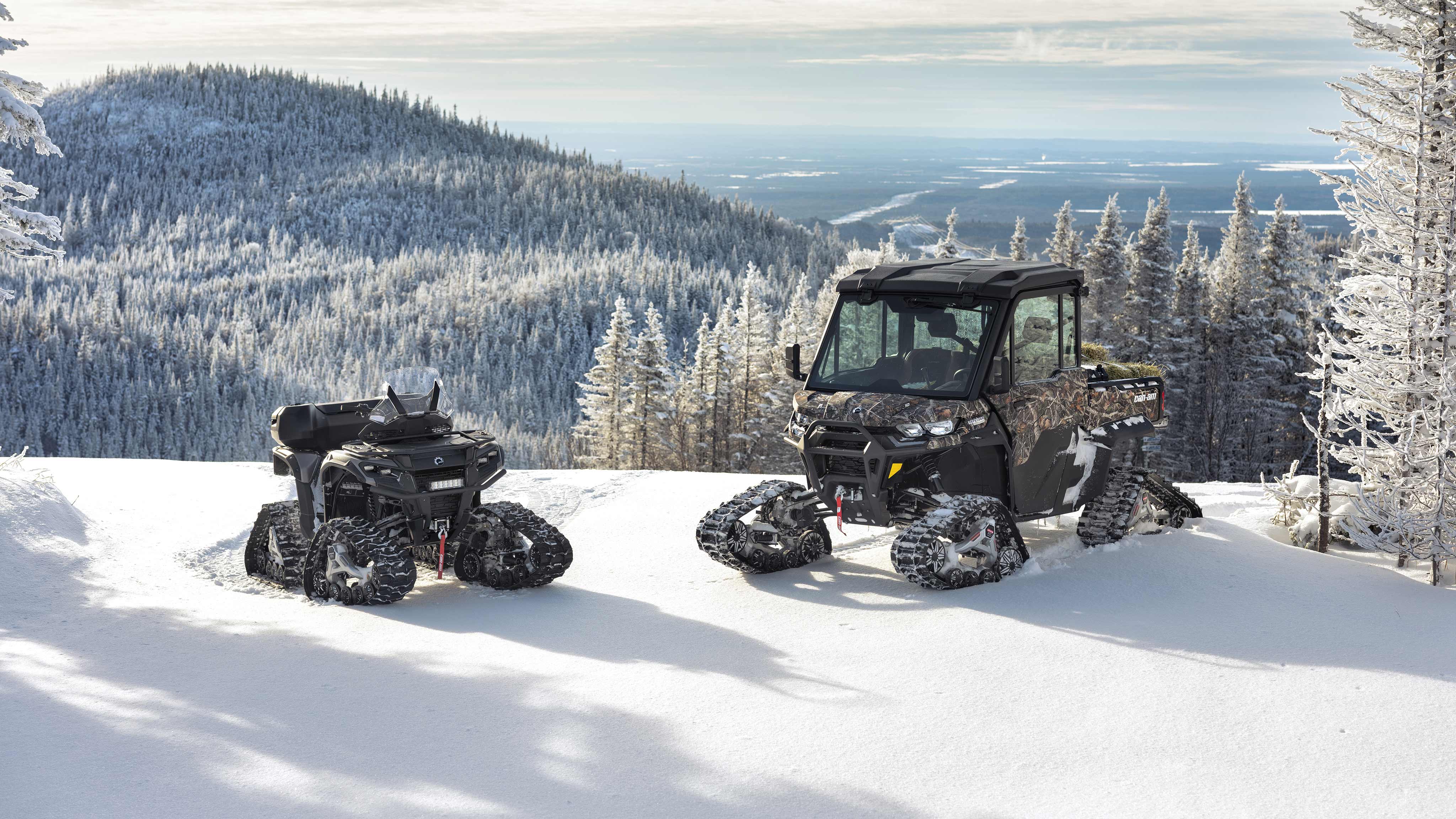 Two Can-Am Off-Road vehicles equipped with Apache track system on top of a snowy mountain