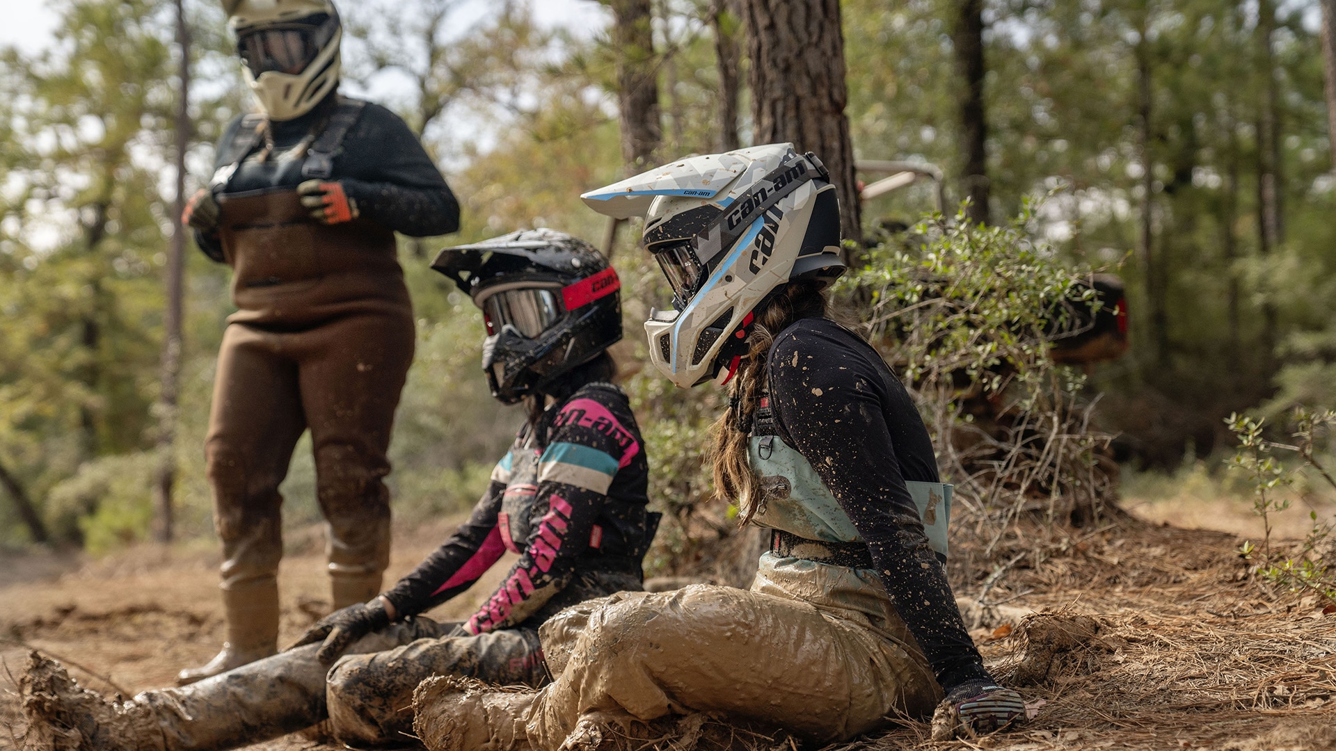 Two female riders wearing Can-Am Off-Road riding gear sitting in the dirt