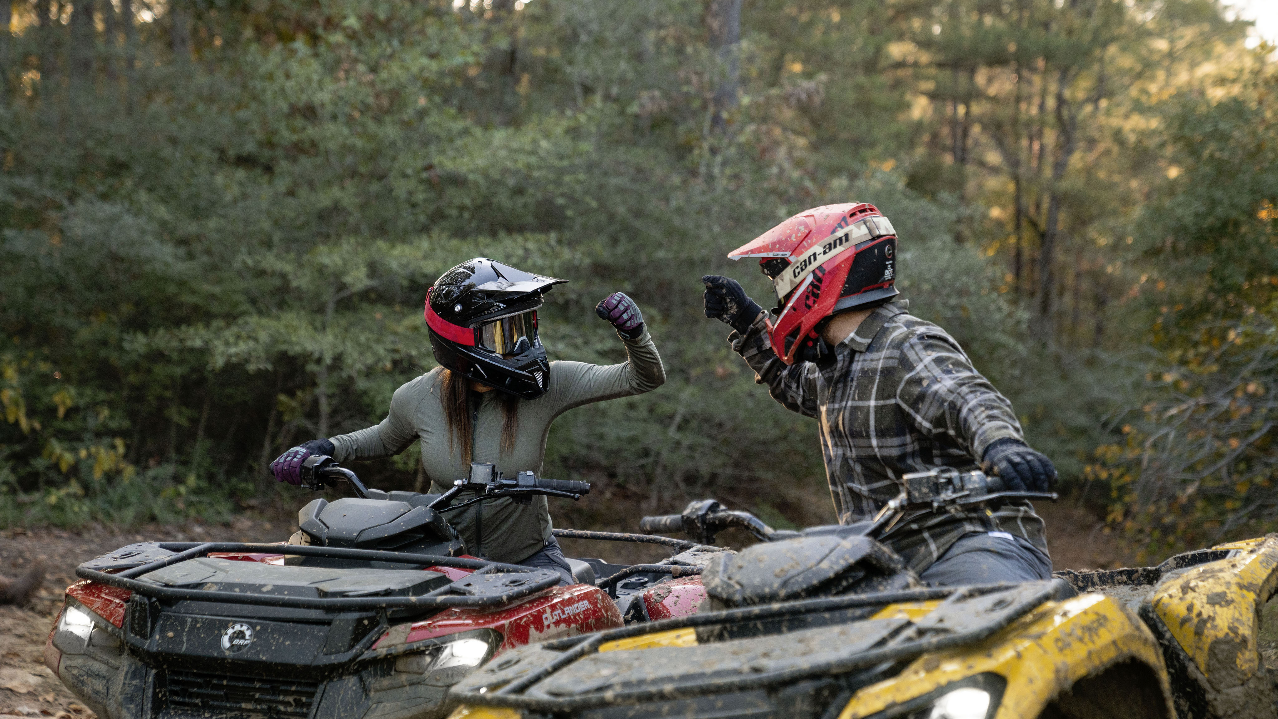 Two Can-Am riders fist bumping from their Can-Am Outlander 500/700 seats