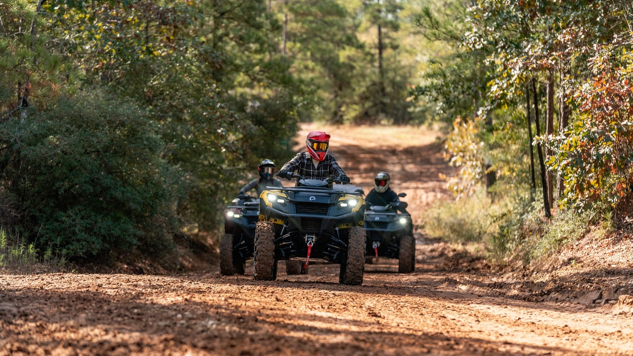 Tres conductores de ATV en línea recta en un sendero