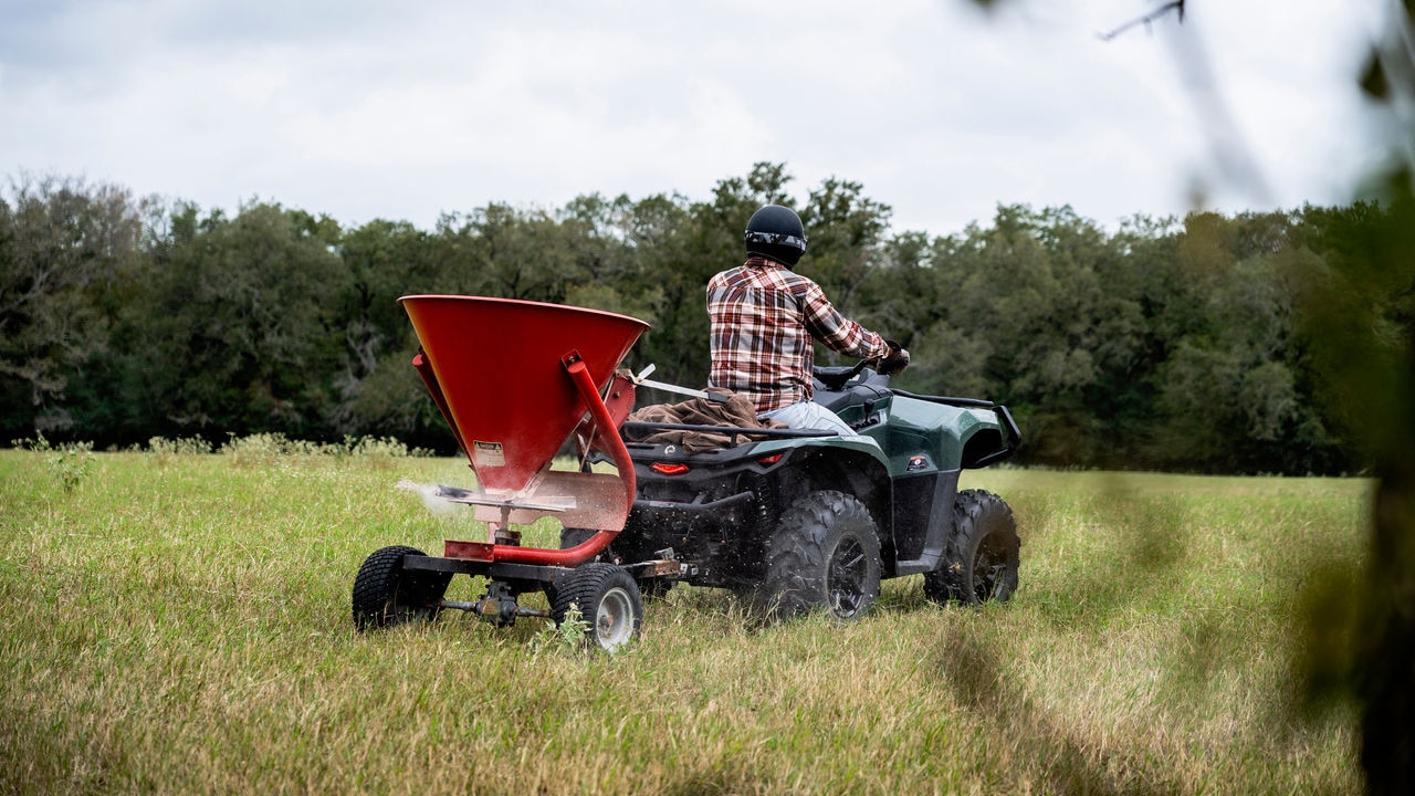 Un agriculteur utilisant son Can-Am Outlander PRO XU pour ensemencer son champ avec la fonction limiteur de vitesse.