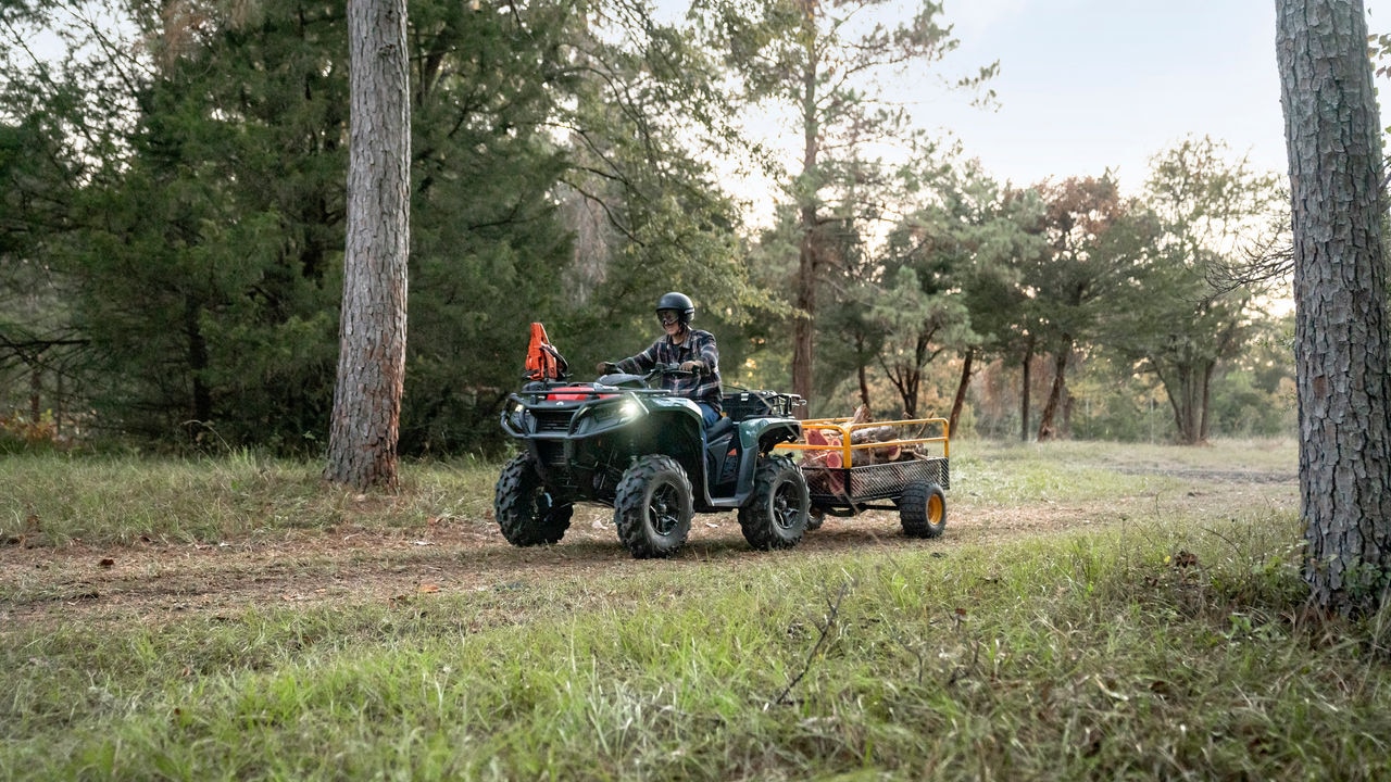 A man hauls wood in a trailer with the Outlander PRO ATV