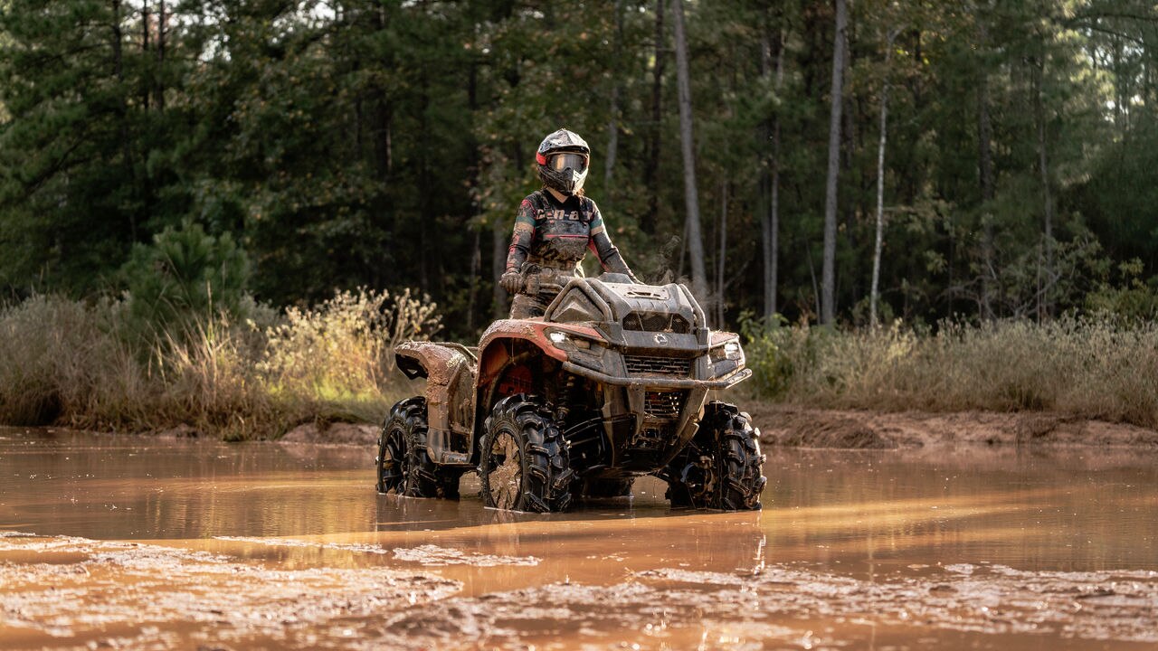 Rider mounting a Can-Am ATV submerged in water