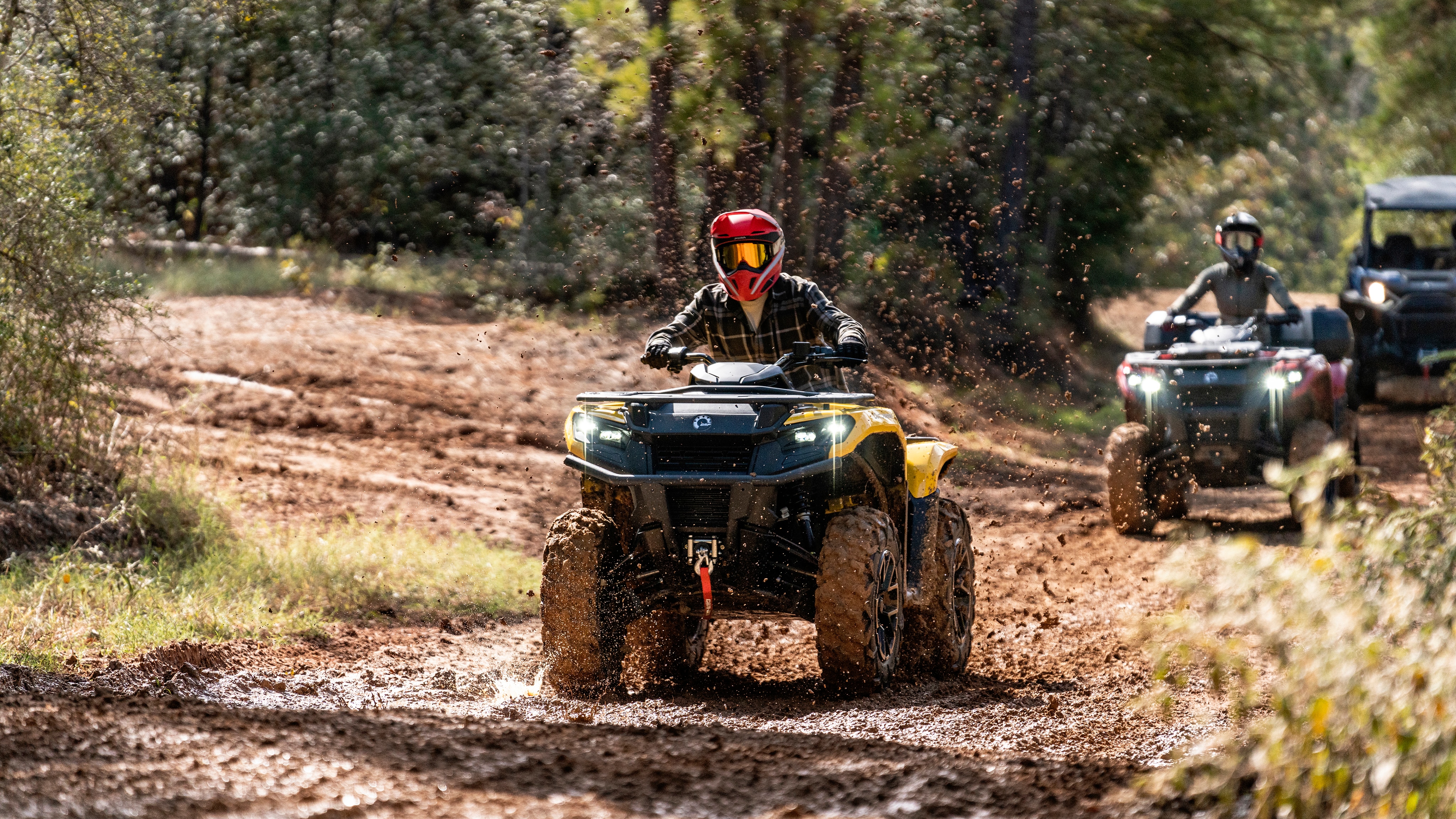Three Outlander 500/700 ATVs following one another on a muddy trail
