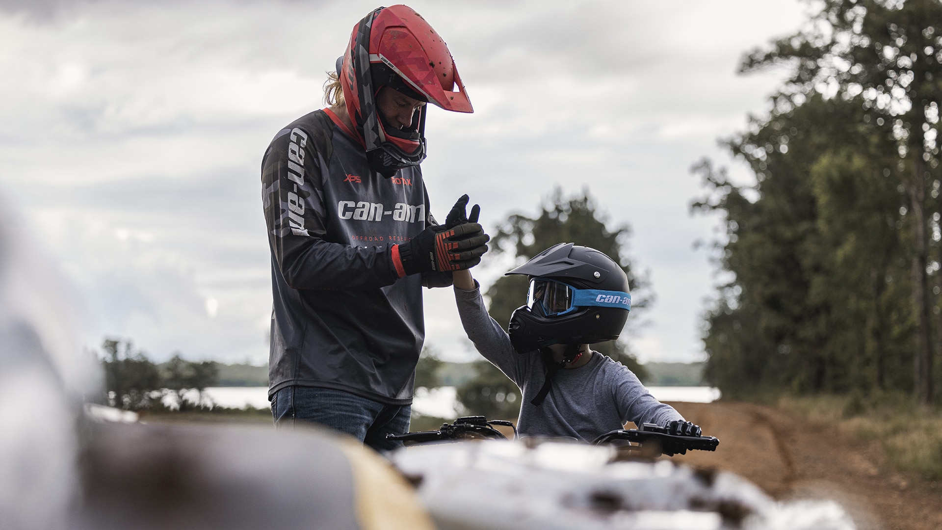 Can-Am Off-Road ambassador Dustin Jones next to his kid sitting on a youth ATV