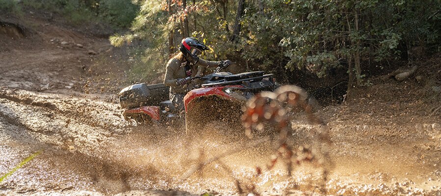Rider passing through a mud hole on her Can-Am Outlander 500/700 ATV
